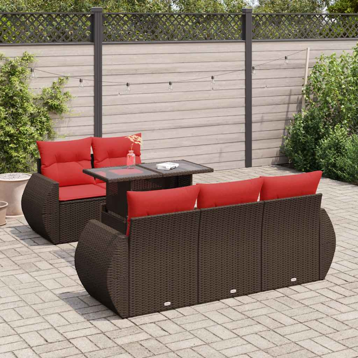 Un sofá y sillón de ratán marrón con cojines rojos en un patio pavimentado.