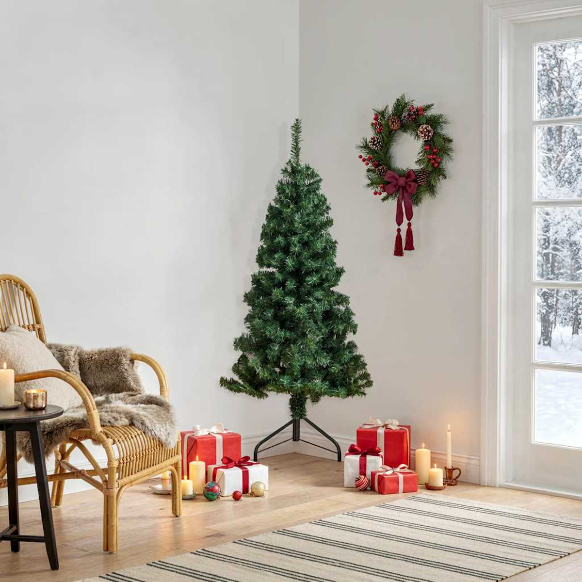 Ein Weihnachtsbaum steht in einer Ecke, geschmückt mit Geschenken und Kerzen.