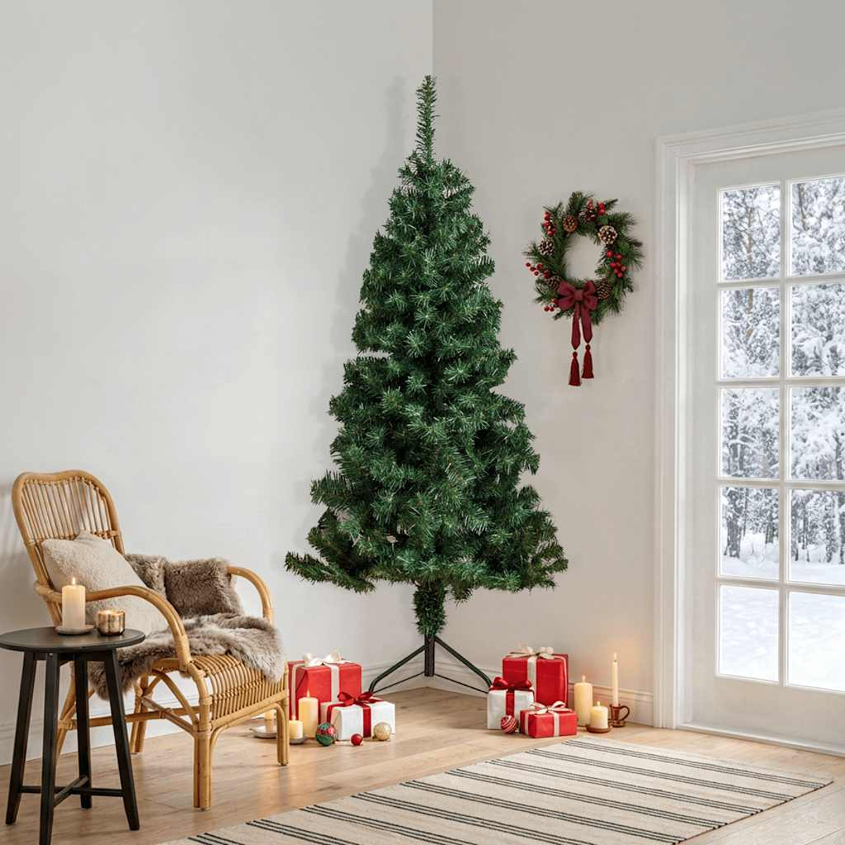 Ein grüner Weihnachtsbaum steht in einem Raum mit Geschenken, einem Stuhl und einem Kranz am verschneiten Fenster.