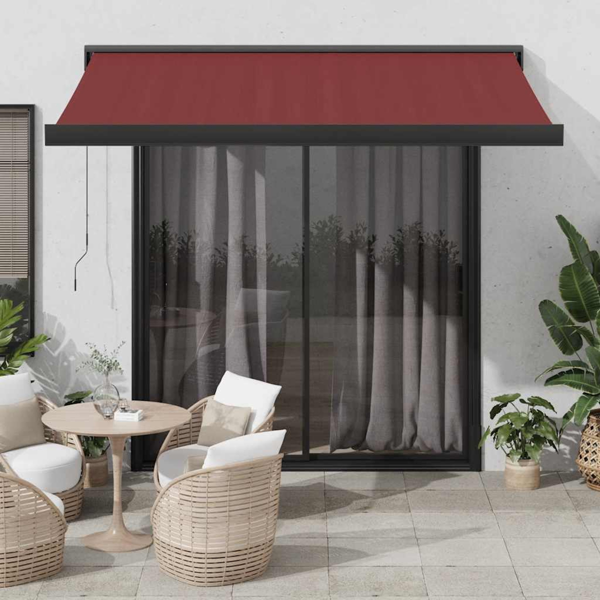 Una tenda da sole rossa sopra una porta del patio con sedie in rattan e un tavolo.