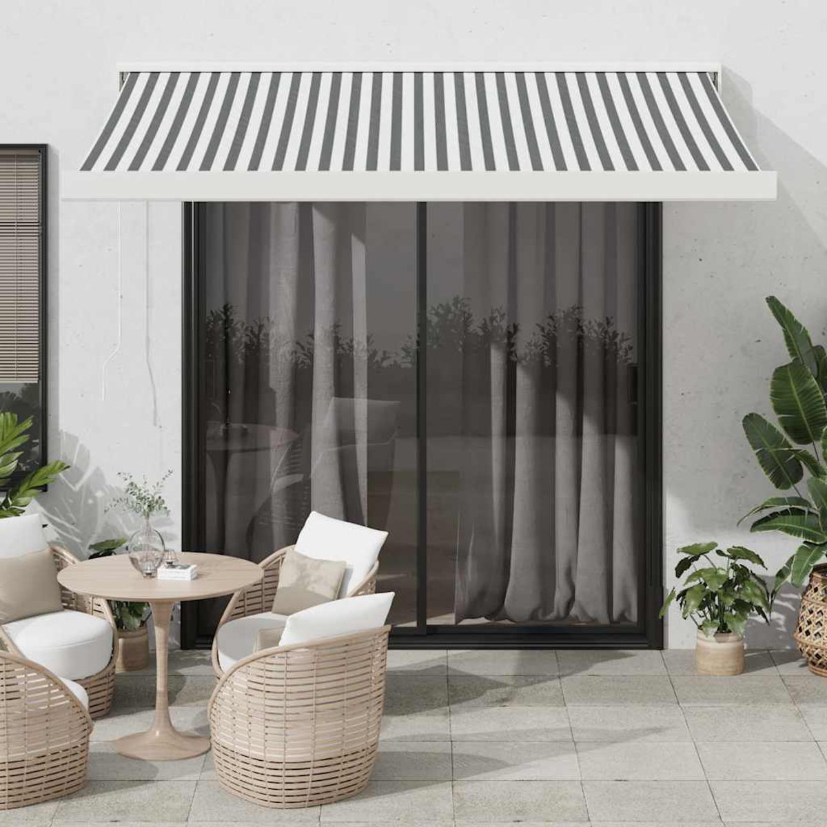 Patio con mobili in rattan, un tavolo e una tenda a strisce.