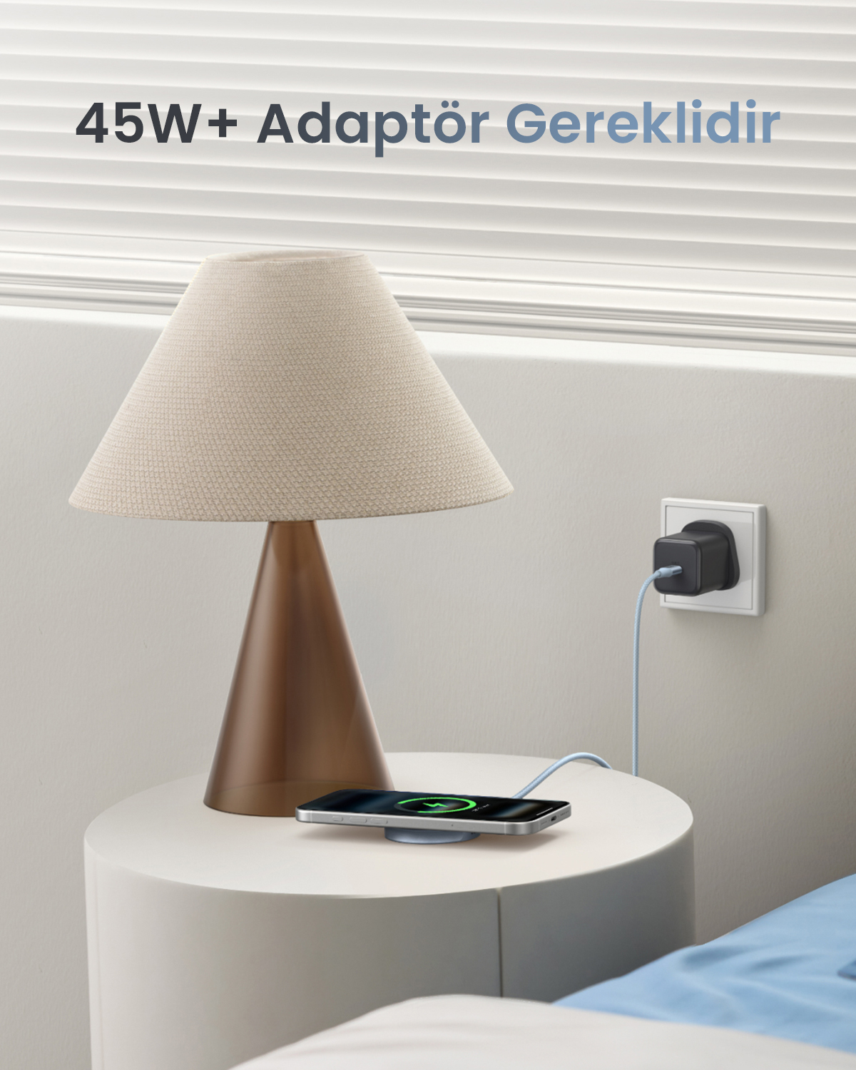 Bir lamba yanında komodinde, adaptöre takılı telefon kablosuz şarj oluyor.