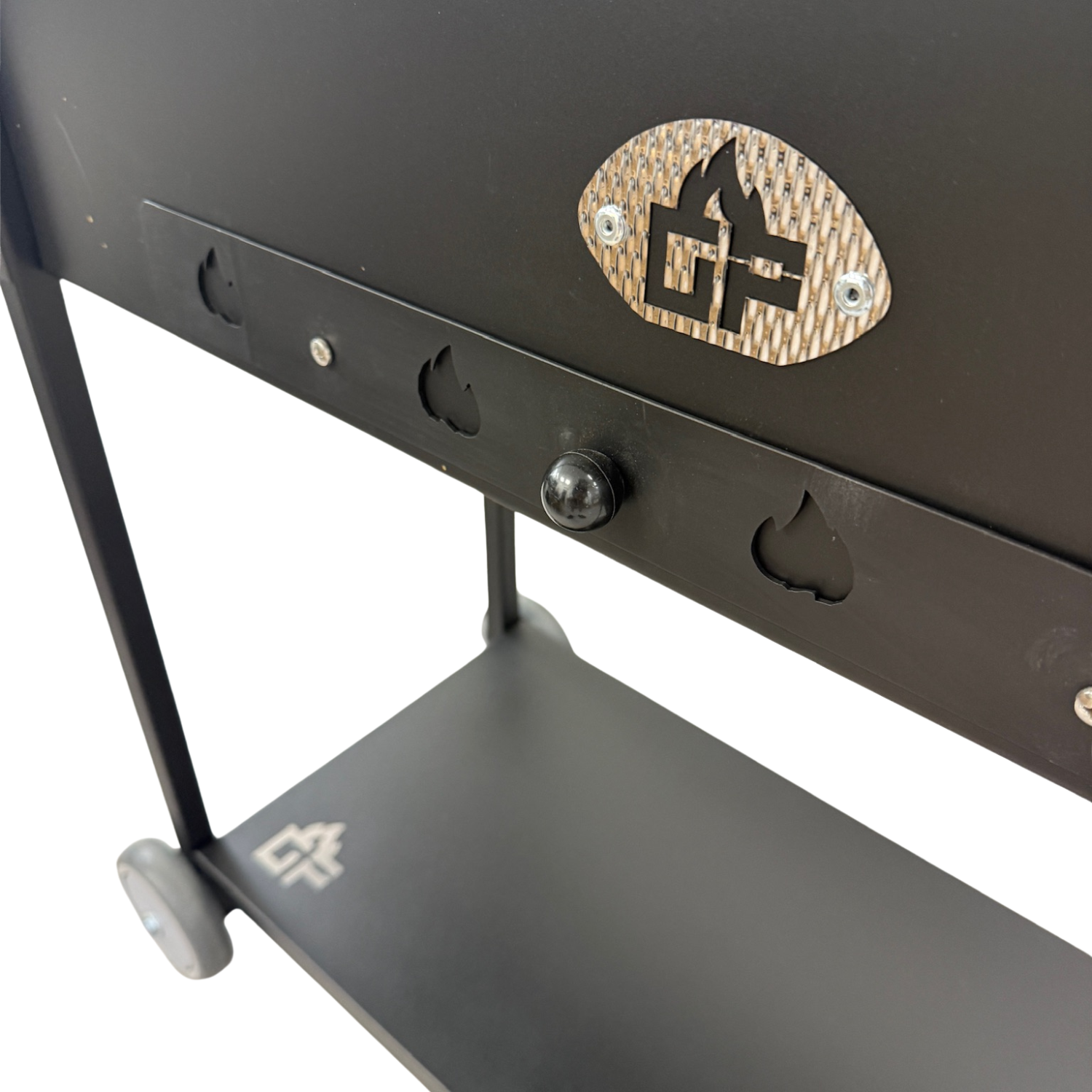 Schwarzer Grill mit Metalllogo, Rädern und Ablage. Flammenausschnitte an der Seite.