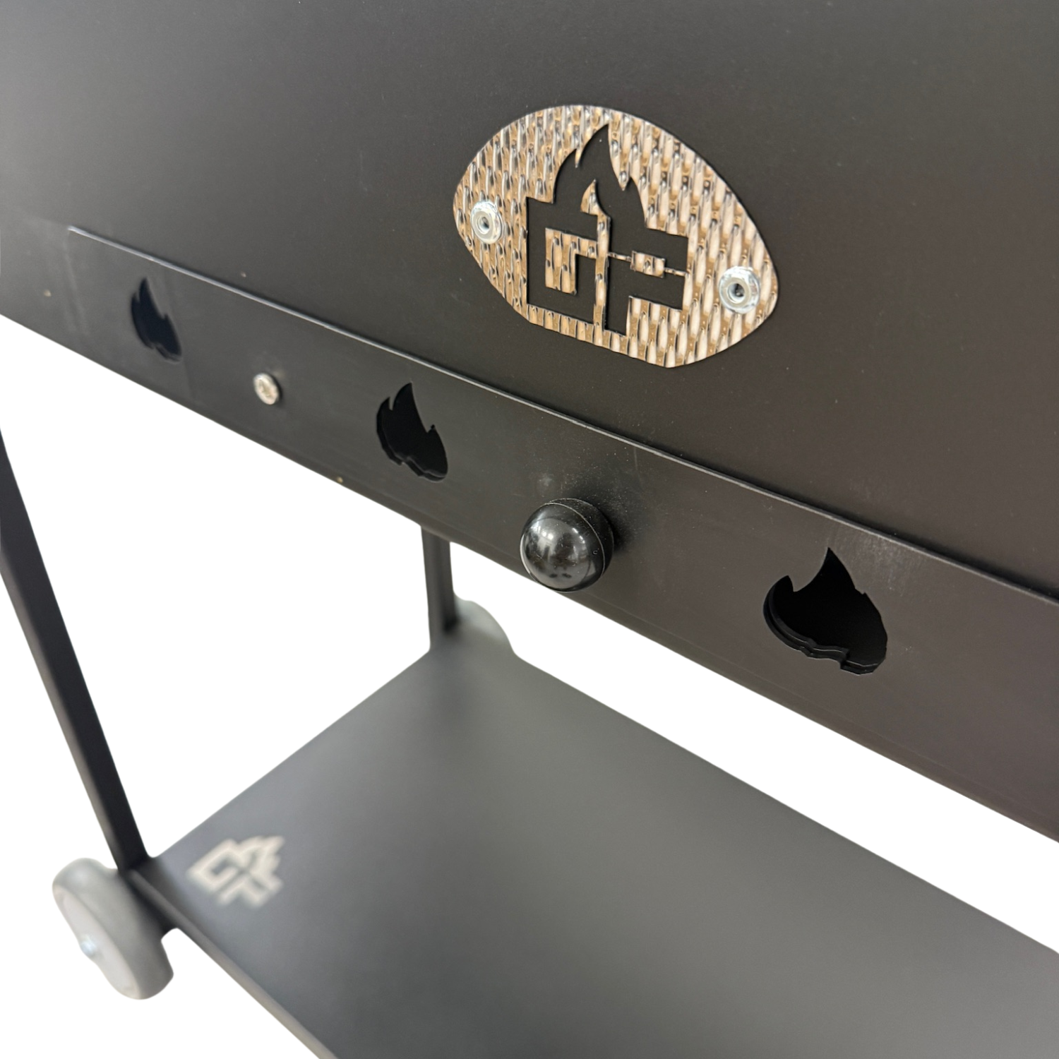 Nahaufnahme eines schwarzen Grills mit Flammenausschnitten und einem ovalen Logo.