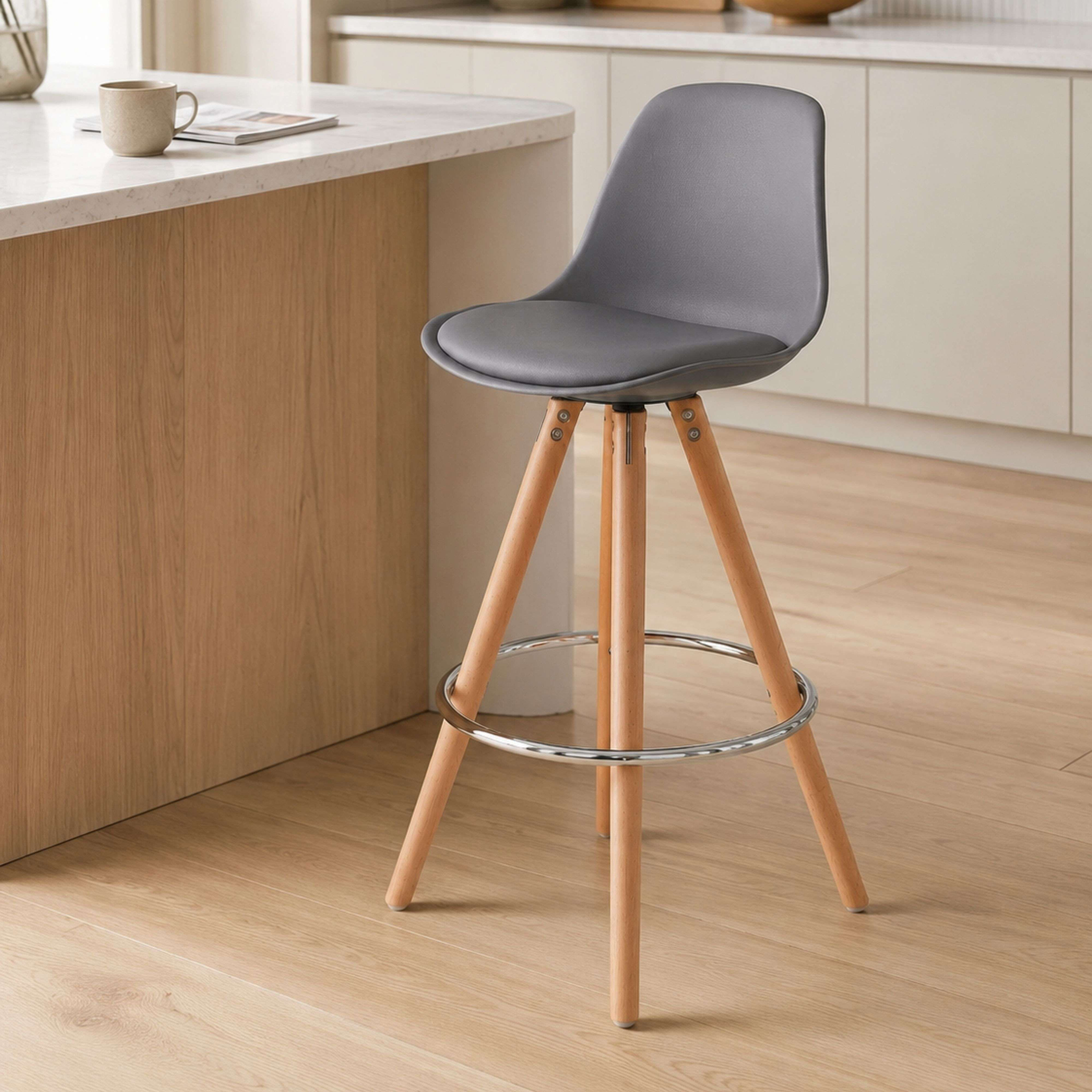Taburete de bar gris con patas de madera y reposapiés metálico en suelo de madera.