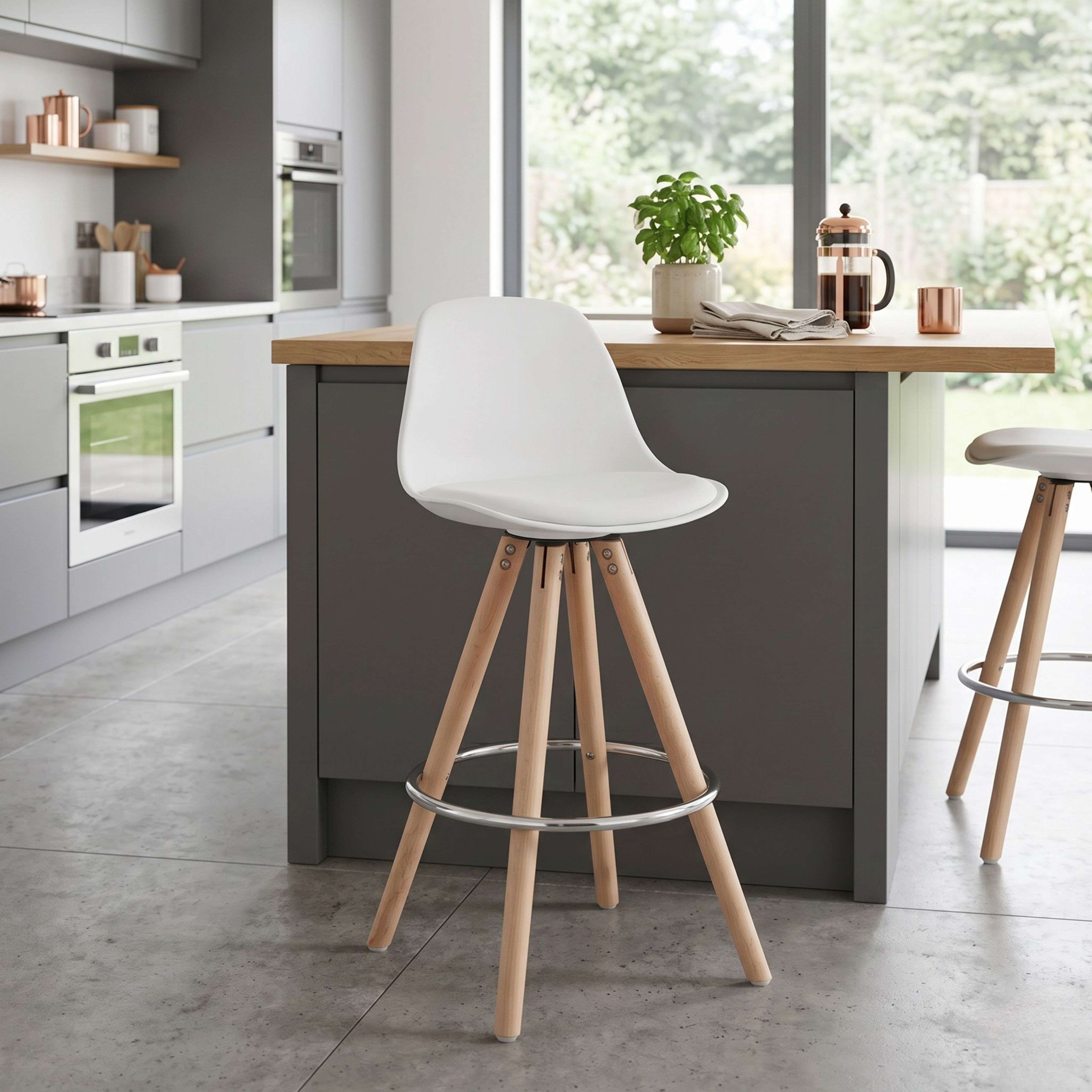 Bancos altos blancos con patas de madera sobre suelo de hormigón en cocina moderna.