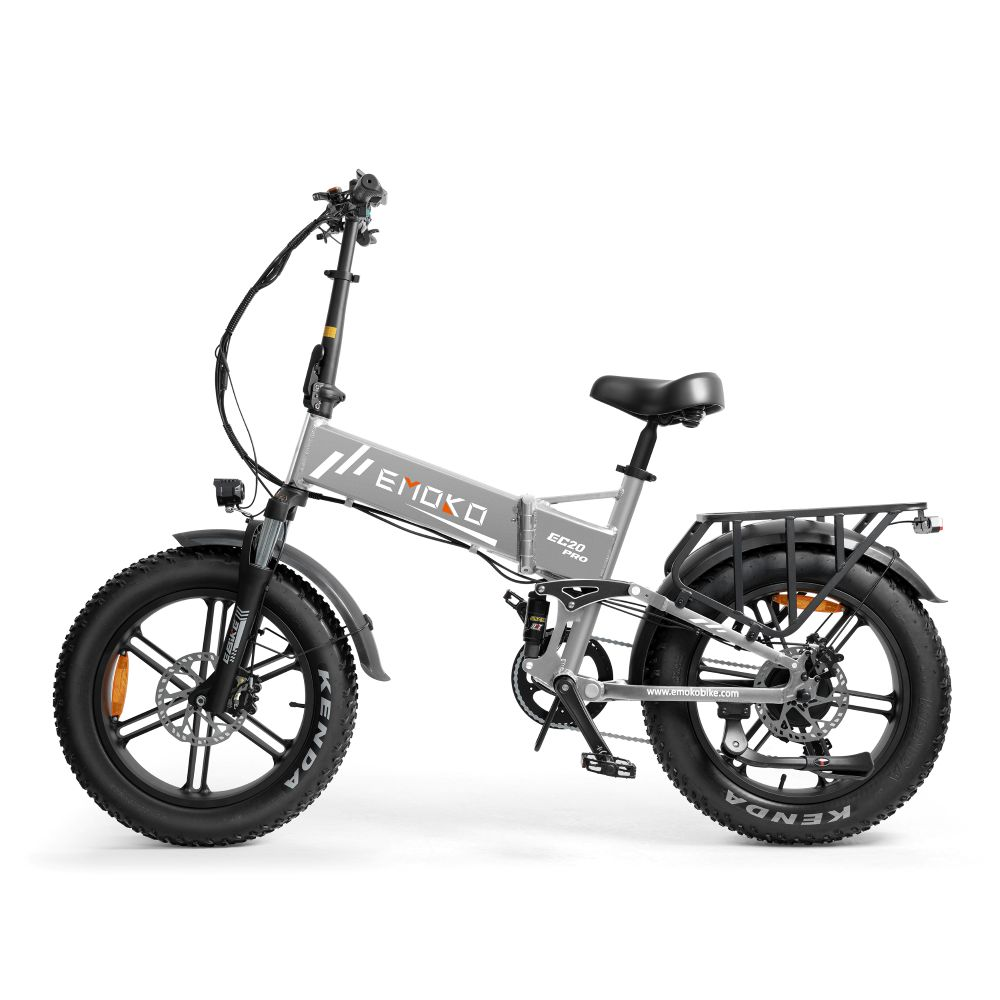 Una bicicleta eléctrica plegable plateada con neumáticos anchos y portaequipajes, aislada sobre fondo blanco.