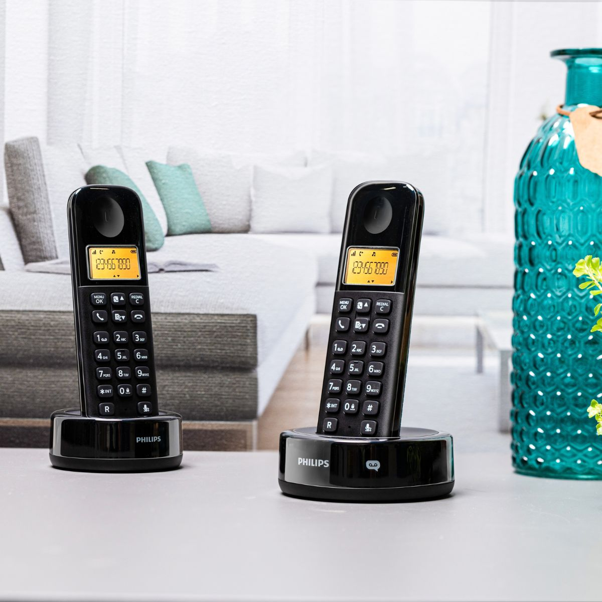 Zwei schwarze Philips Schnurlostelefone mit gelbem Display stehen auf einer Tischplatte.