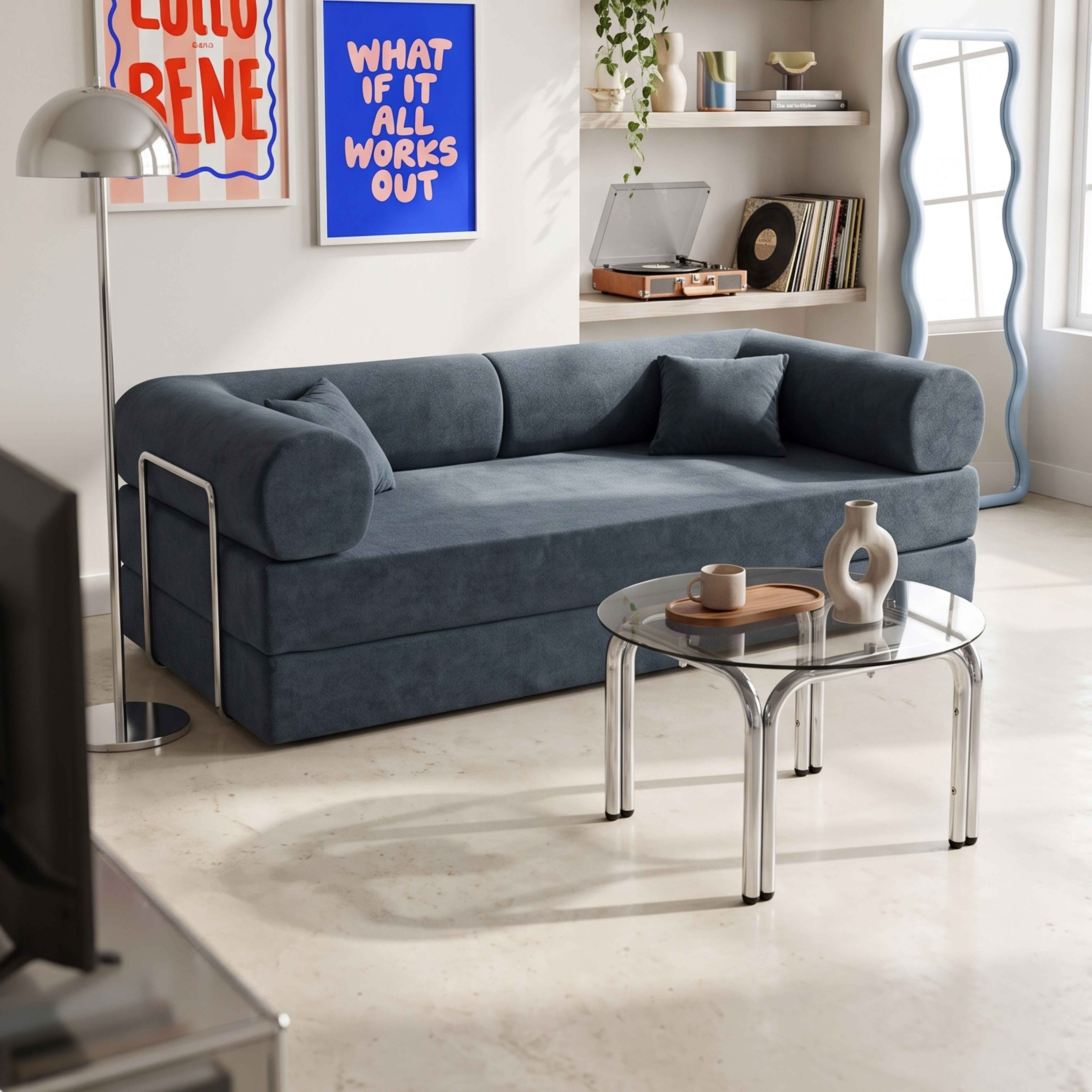 Ein blaues Sofa mit runden Armlehnen steht vor einem Couchtisch aus Glas und Chrom.