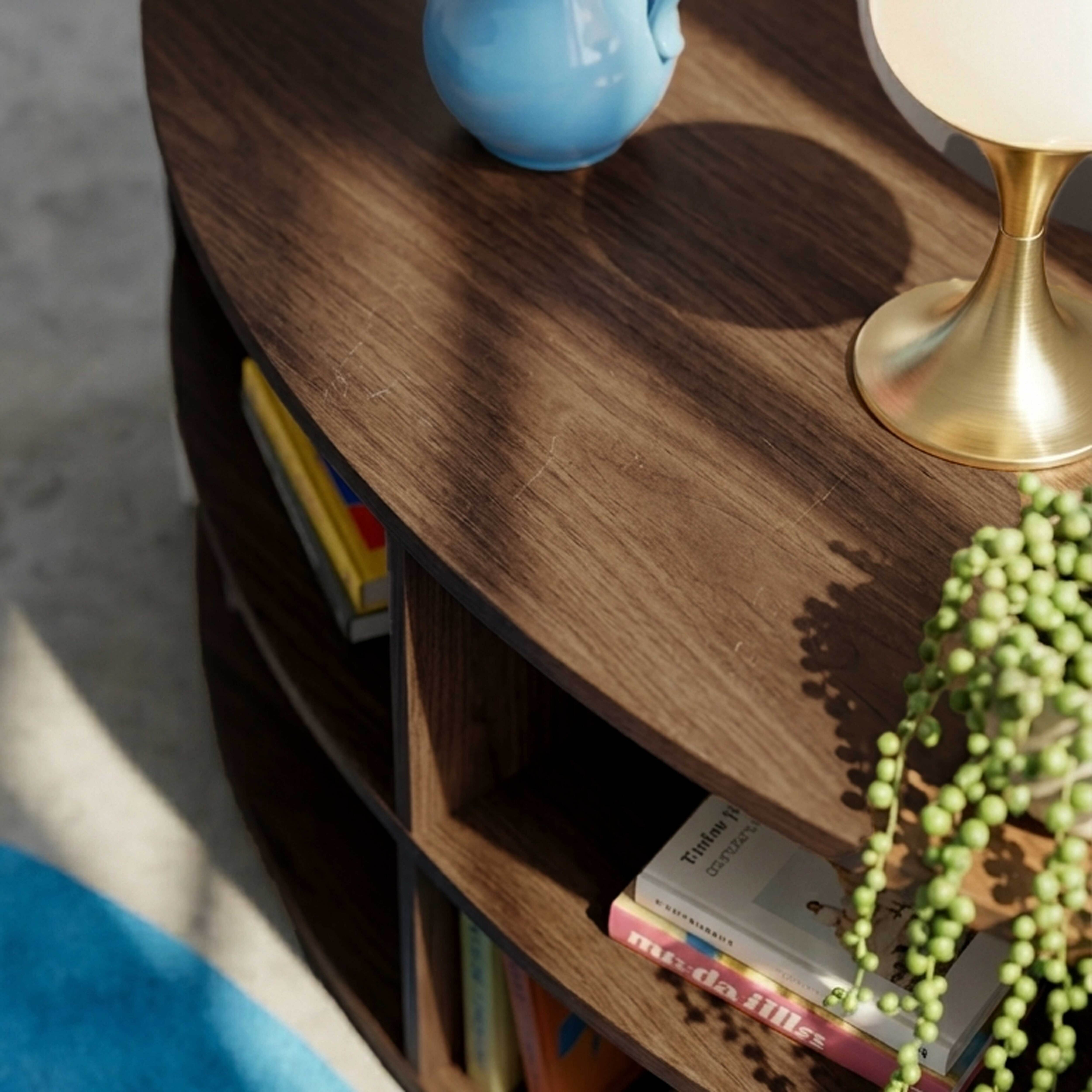 Ein blaues Krug, Lampe, Bücher und eine Pflanze auf einem Holztisch.