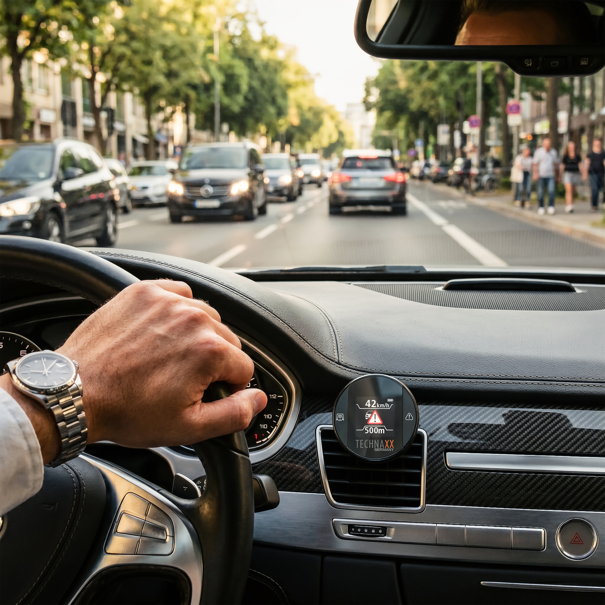 Fahrerhand am Lenkrad, Blick auf die Straße mit Verkehr und Bäumen.