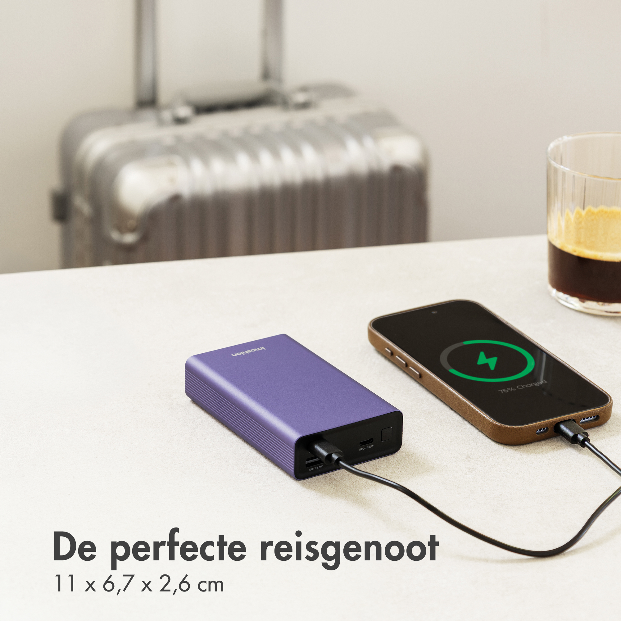Purple power bank charges phone, near suitcase and coffee. Travel note.