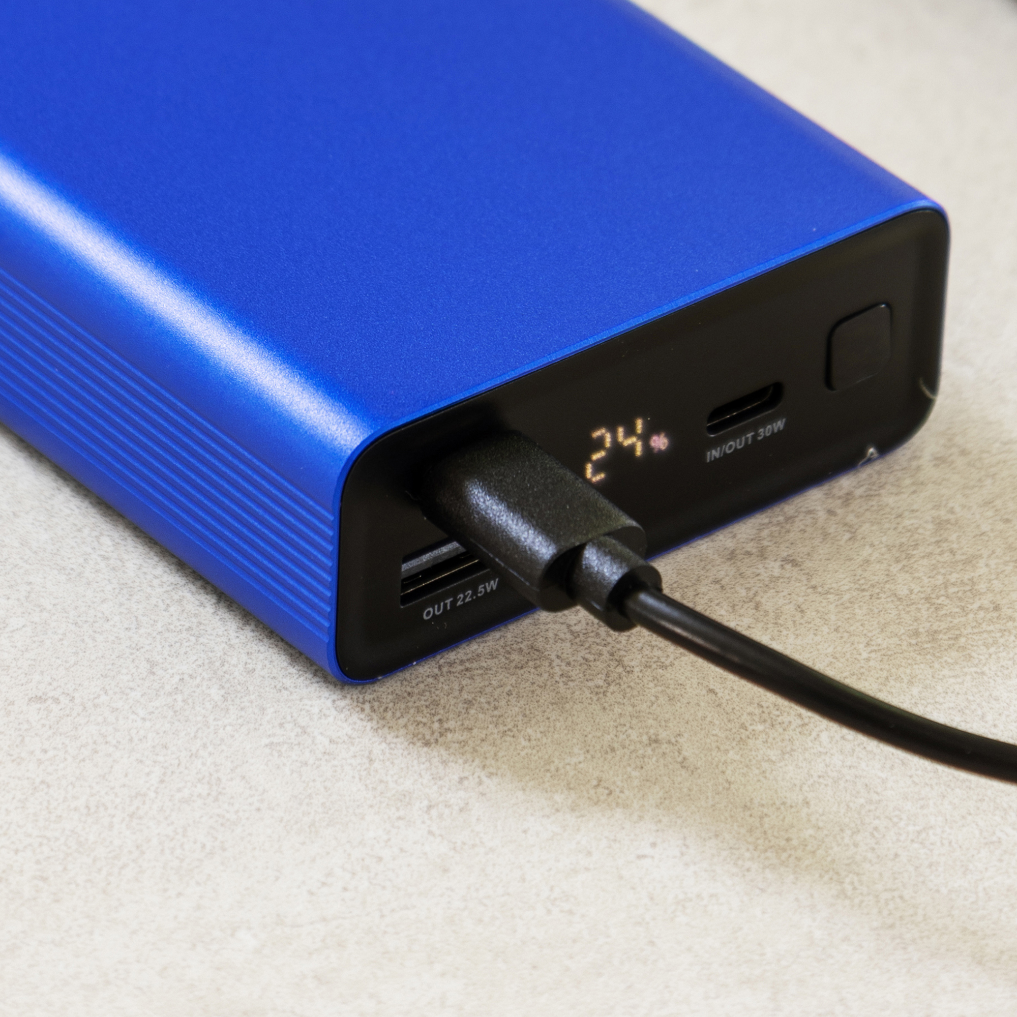 A blue power bank with a black cable plugged into its USB port.
