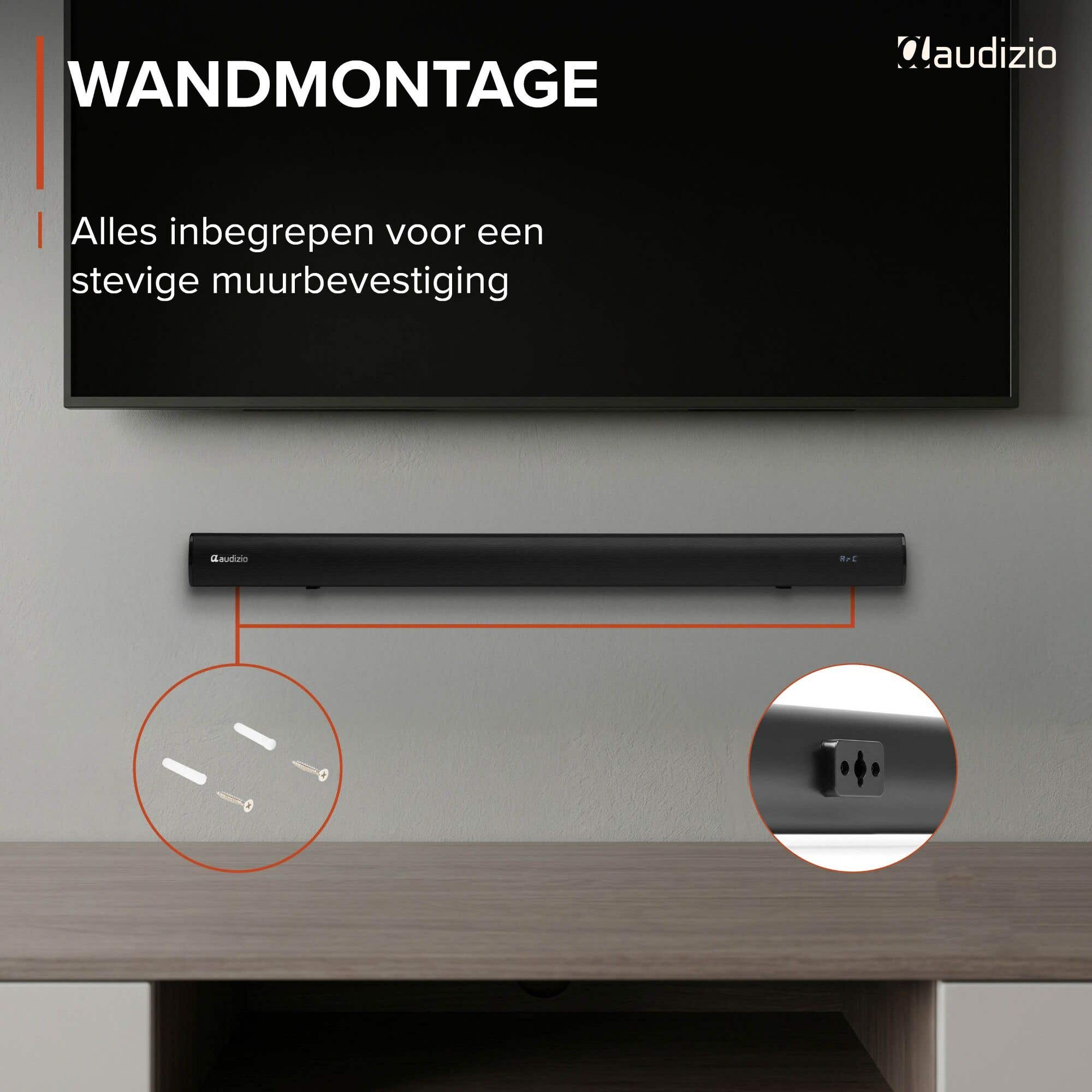 Barra de sonido negra montada debajo de un televisor en una pared gris.