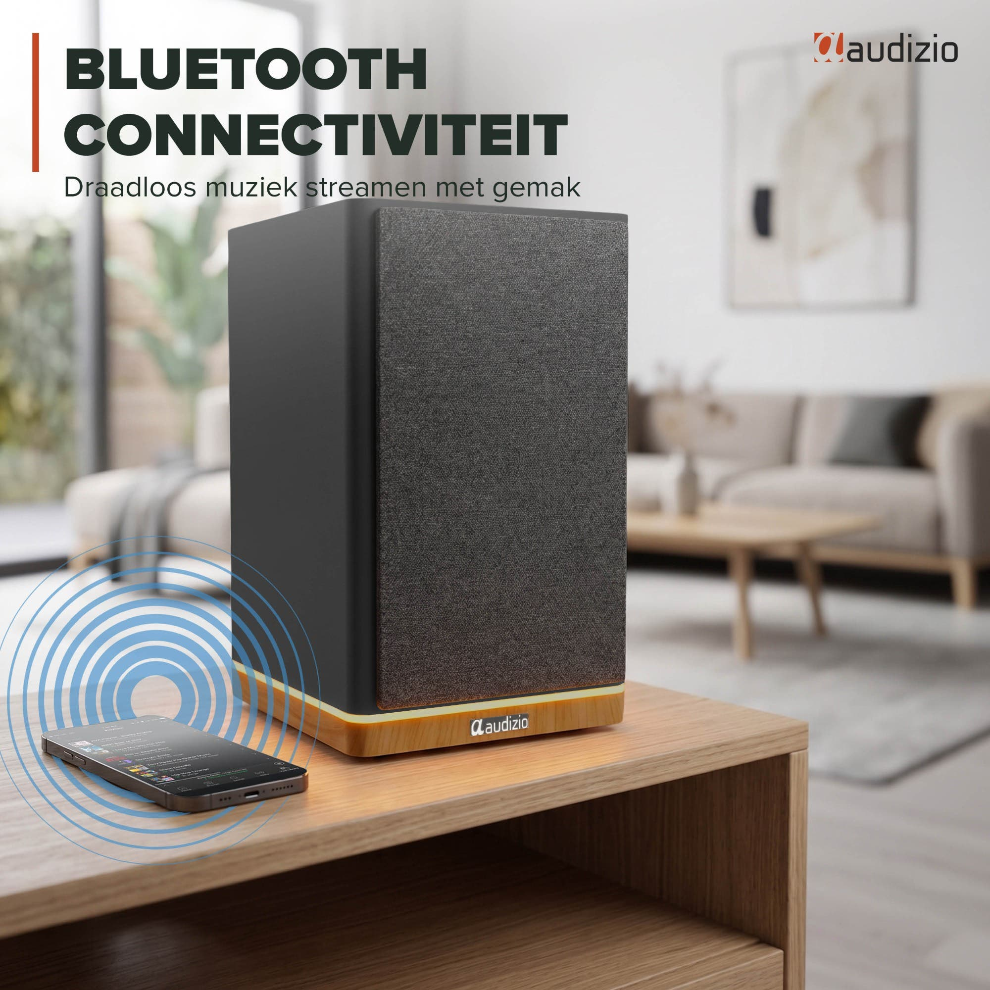 Un altavoz negro con base de madera y un smartphone con app de música sobre mesa de madera.