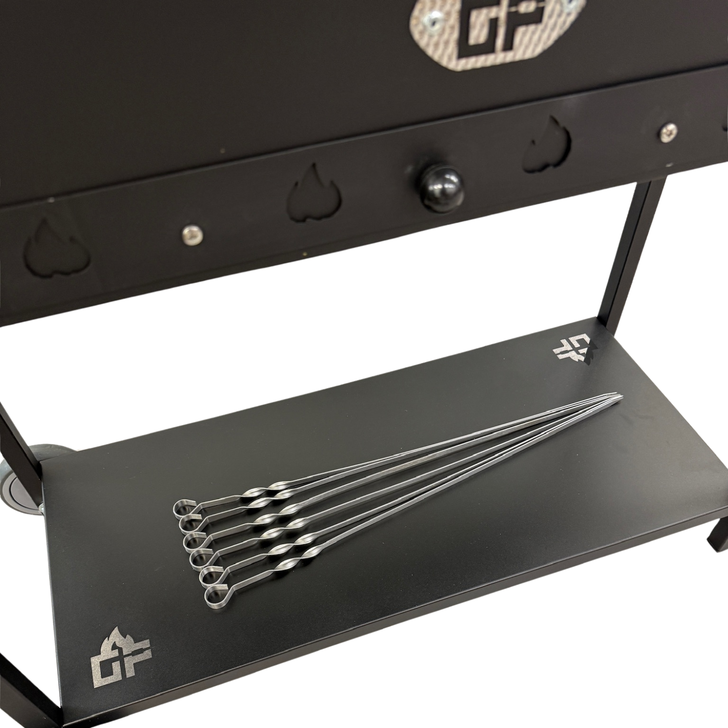 Ein schwarzer Grill mit fünf Metallspießen auf dem unteren Regal.