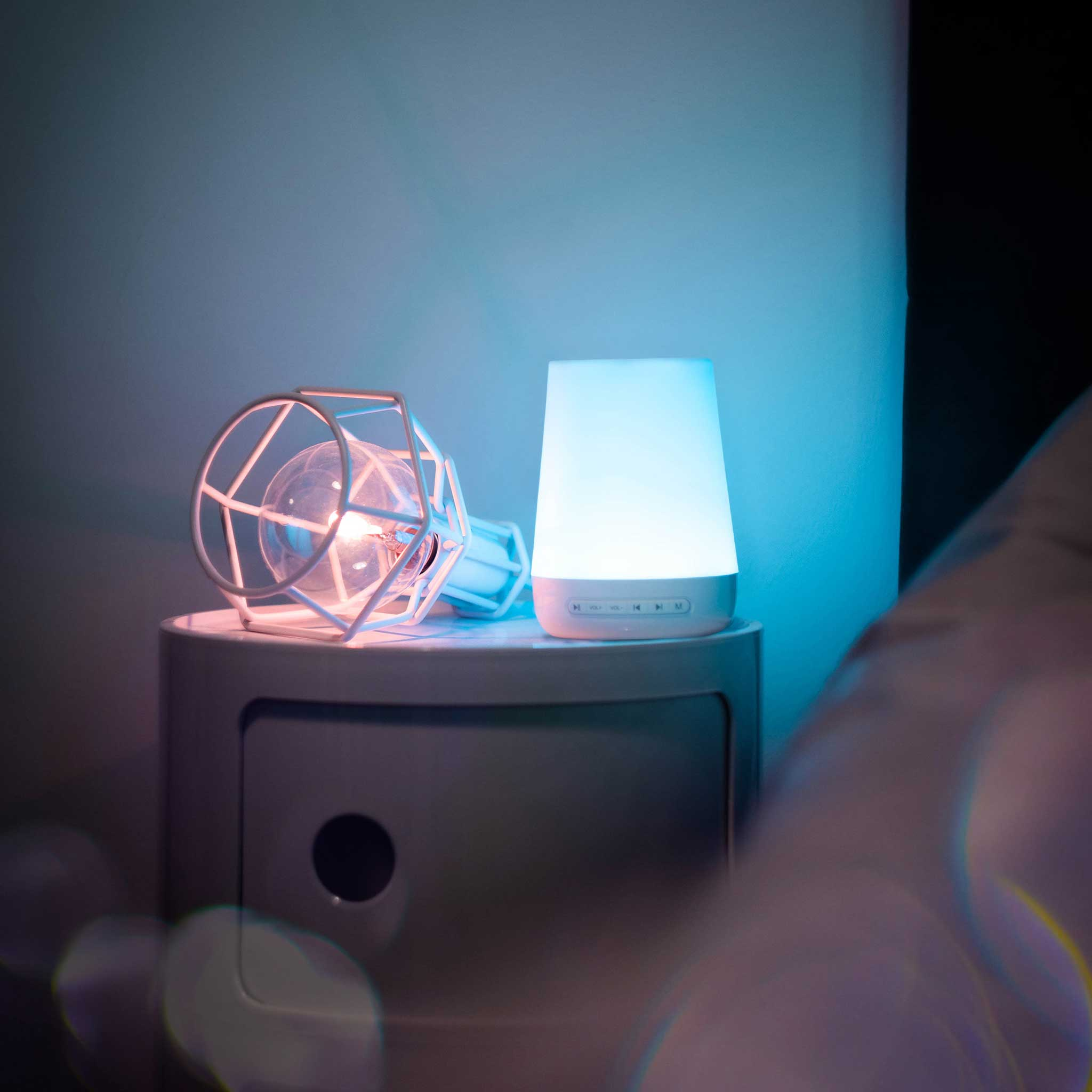 Ein Nachttisch mit zwei Lampen, eine davon beleuchtet, eine andere leuchtet blau.