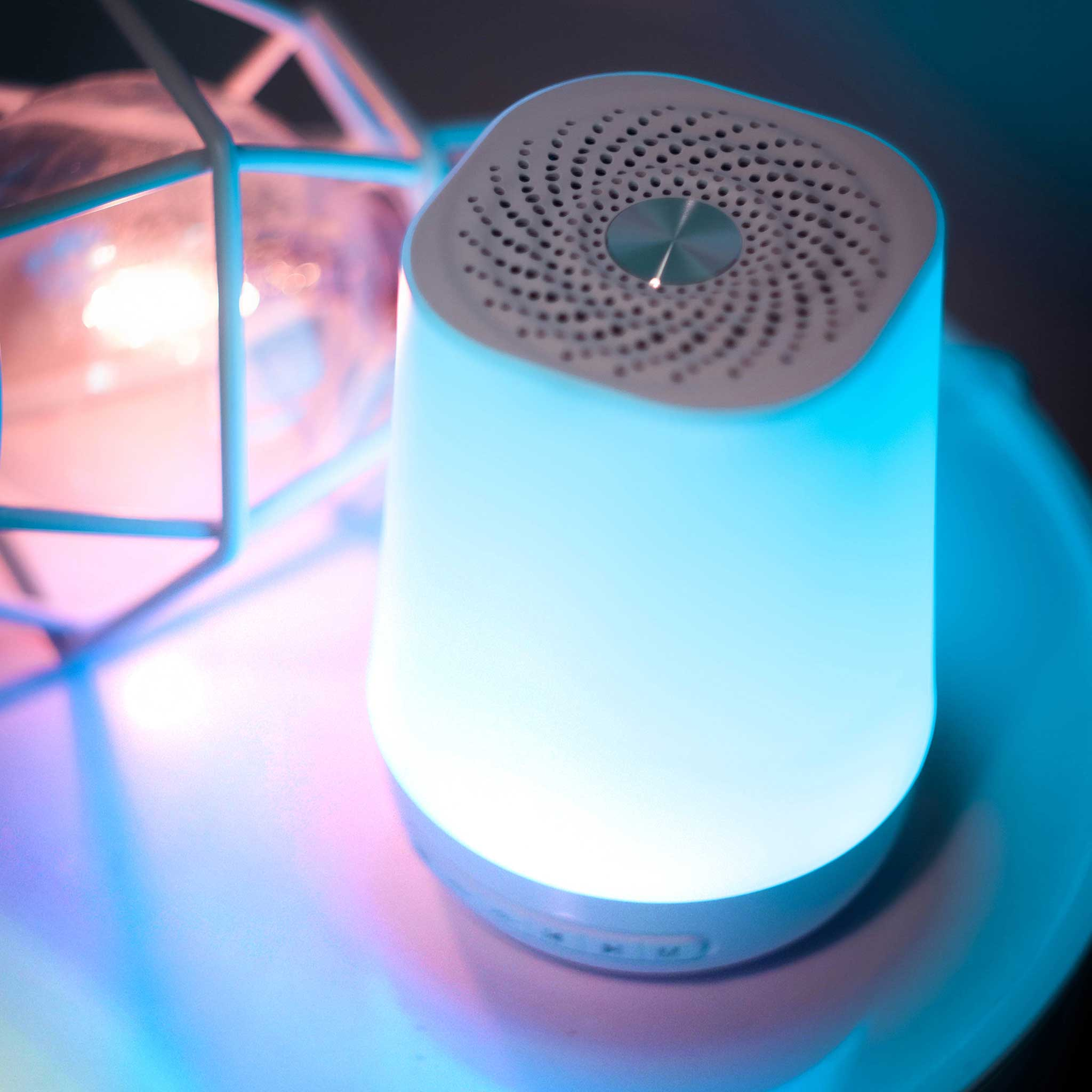 Eine weiße Lampe mit blauem Licht neben einem geometrischen Metallgestell.
