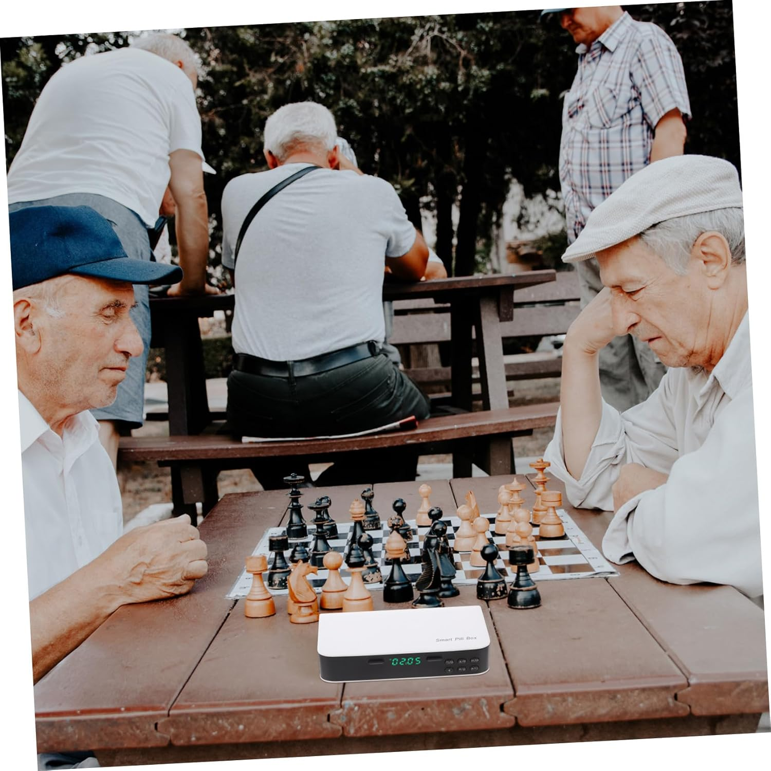 Ältere Männer spielen Schach im Freien an einem Holztisch.