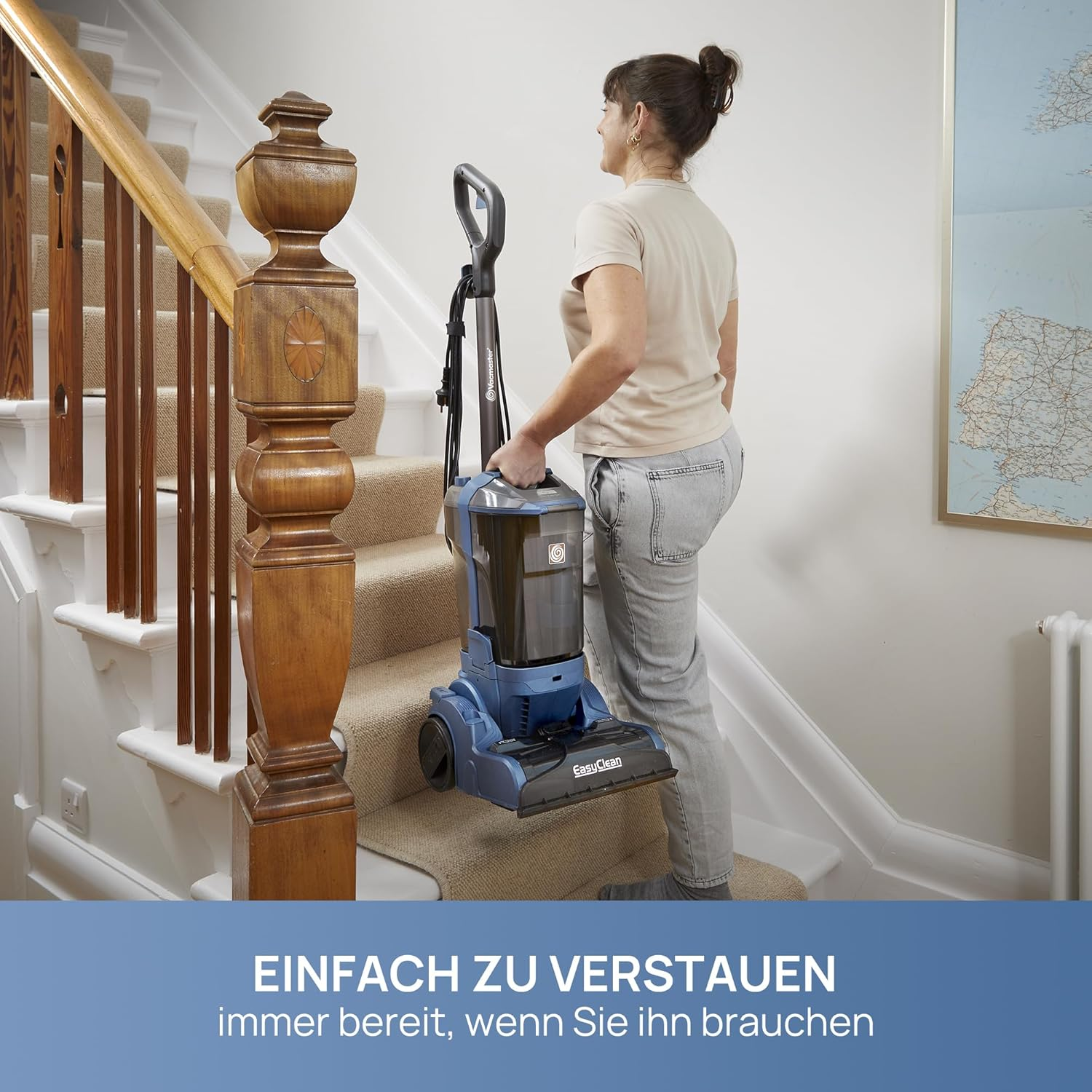 Eine Frau trägt einen blauen Staubsauger die Treppe hinauf. Ein Holzzaun ist an der Seite.
