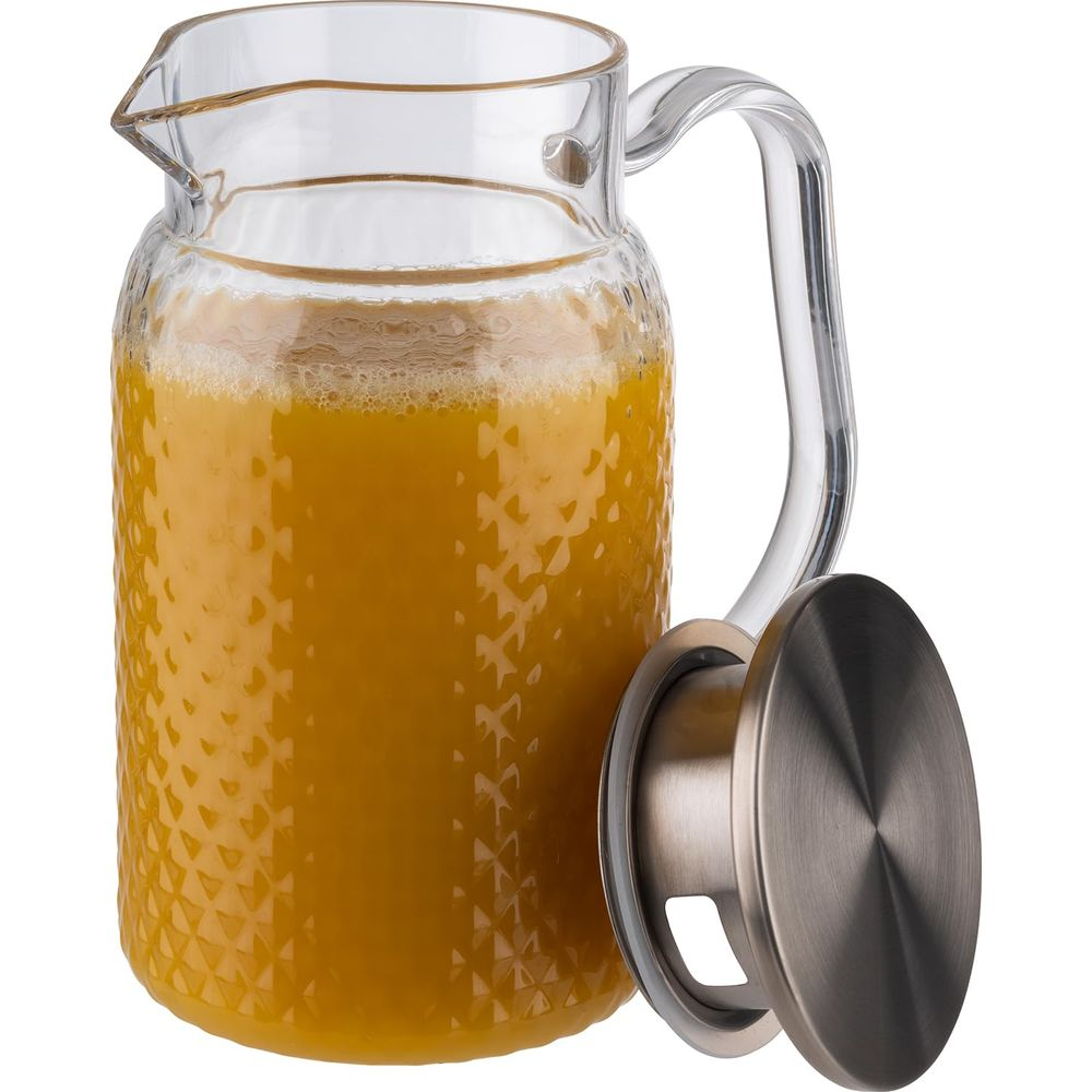 Ein Glaskrug mit strukturierter Oberfläche ist mit Orangensaft gefüllt und hat einen Metalldeckel.