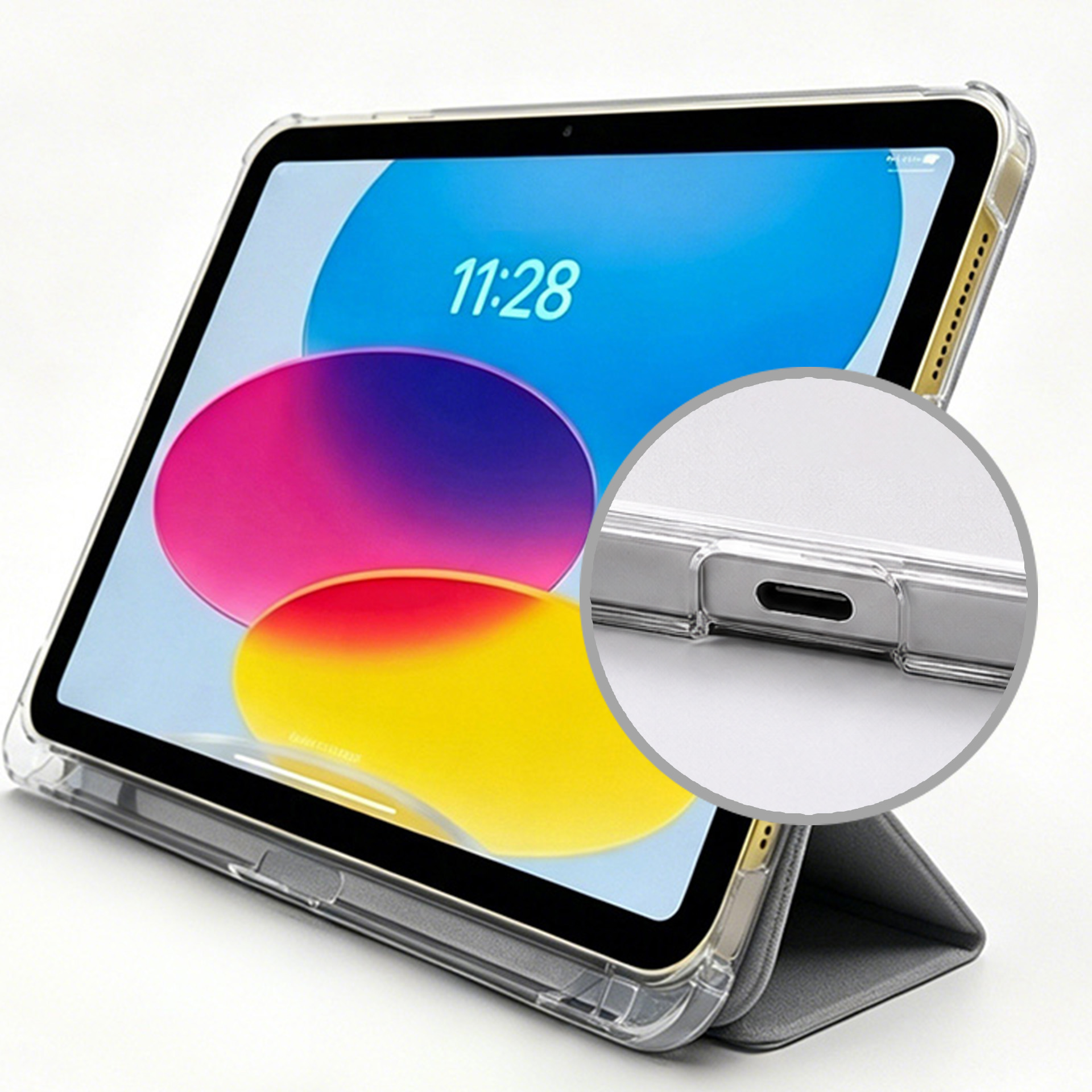 Tablet w przezroczystym etui stoi na szarej podstawce. Zbliżenie portu ładowania.