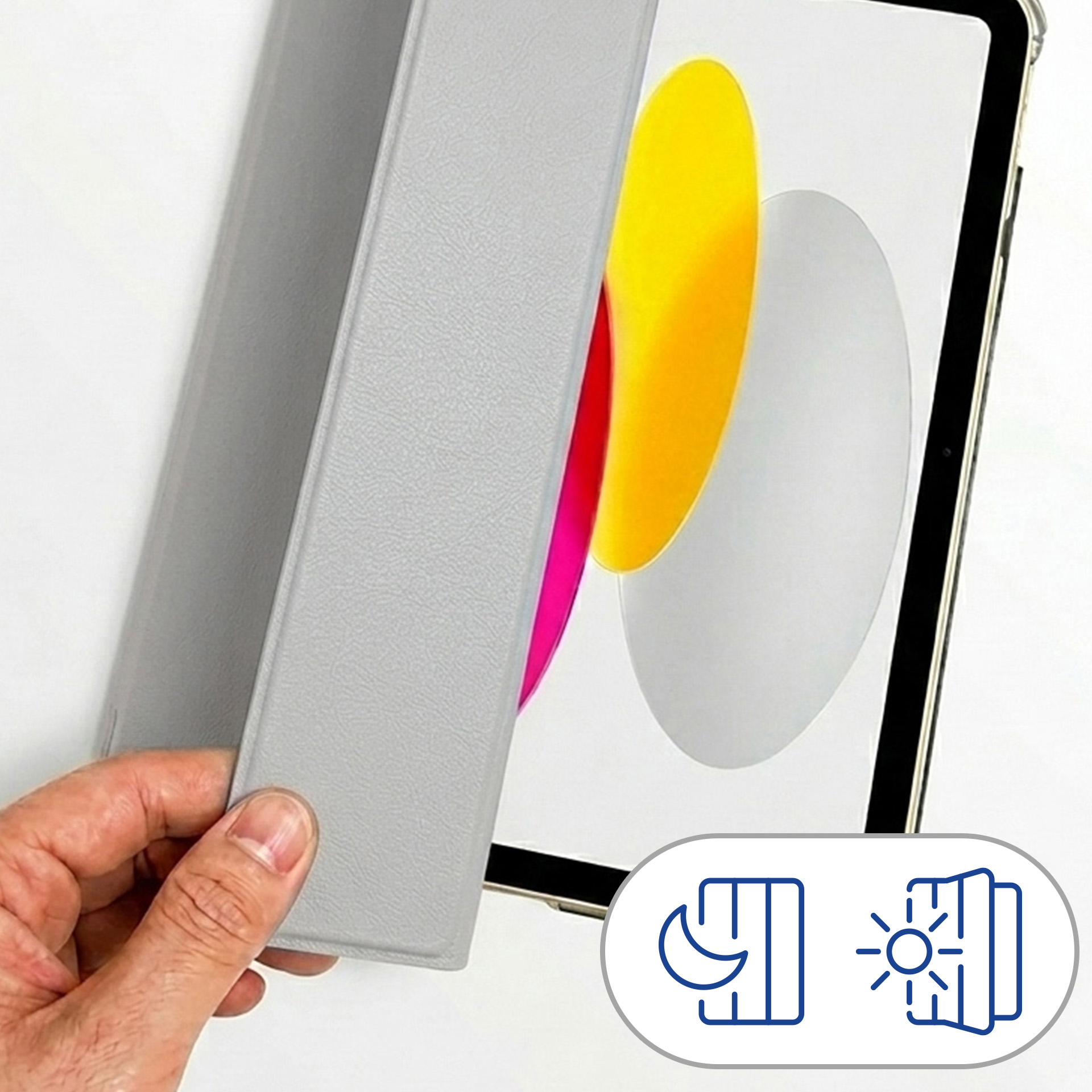 Dłoń otwiera szarą okładkę tabletu, odsłaniając tablet z kolorową tapetą.
