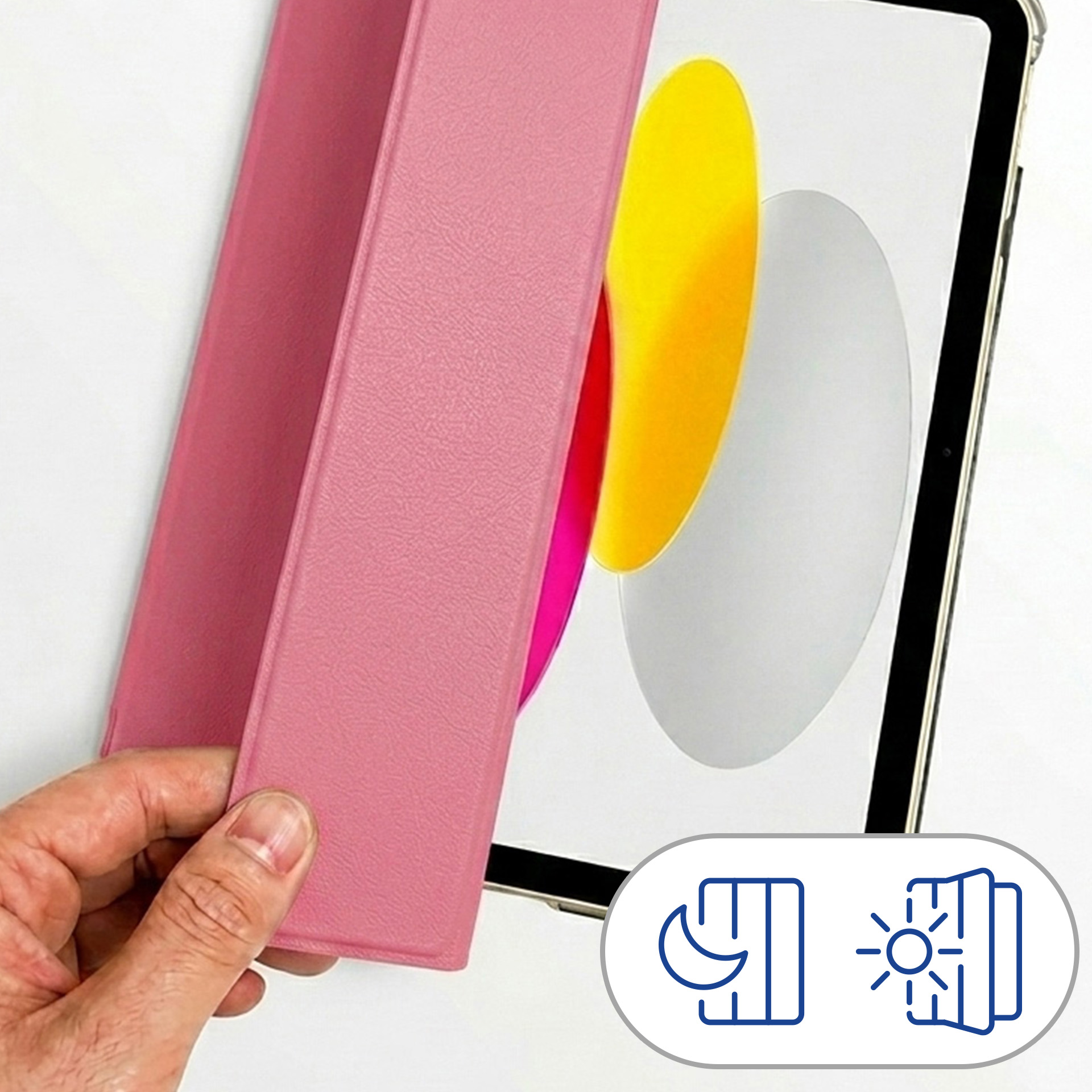 Ręka trzyma różowe etui na tablet przed tabletem.