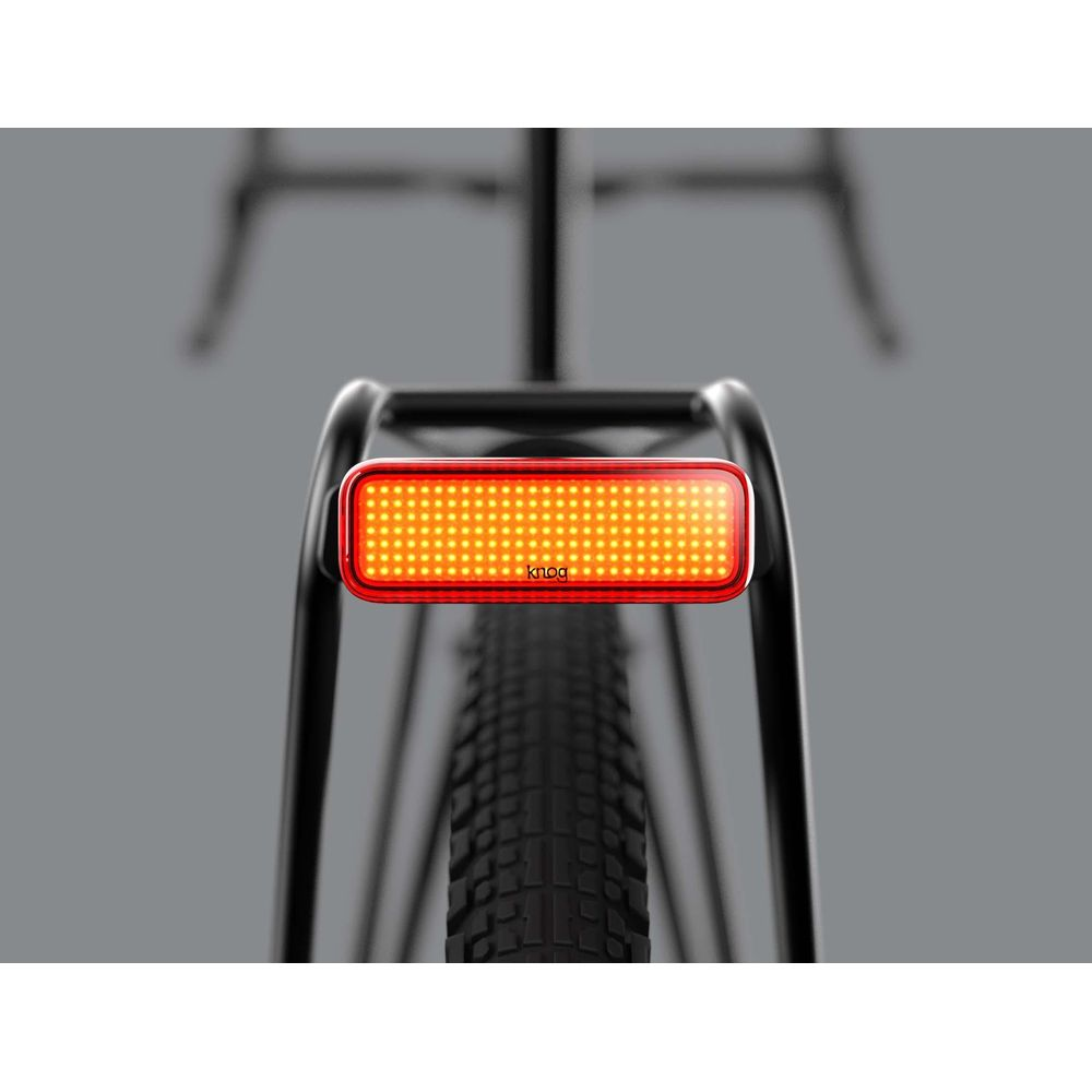 Ein rotes Rücklicht mit vielen orangen LEDs leuchtet auf einem Fahrradträger.