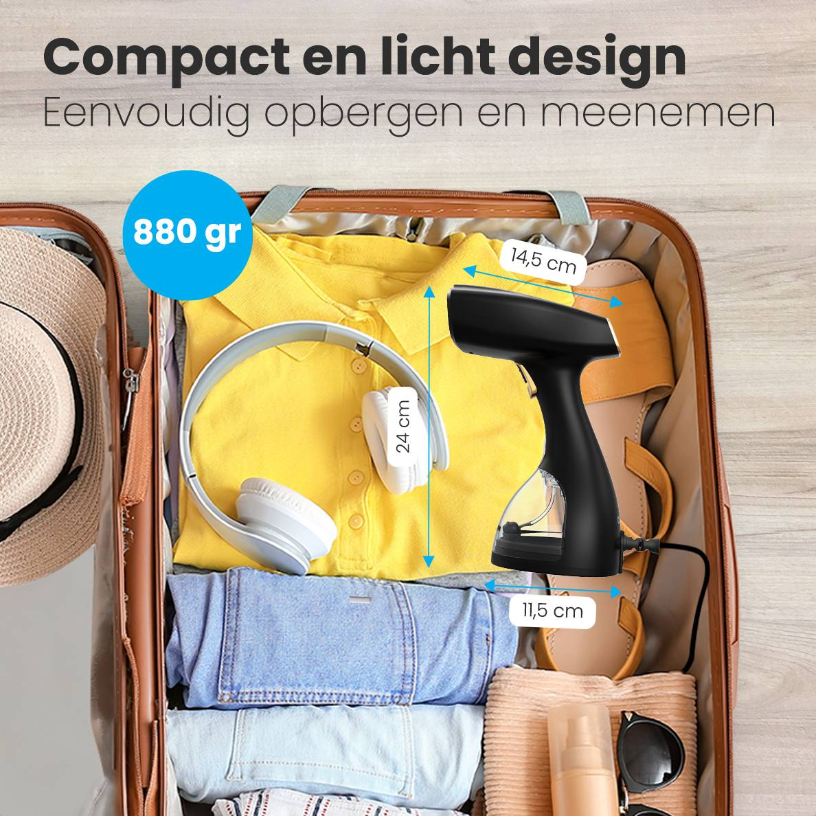 Schwarzer Handdampfer in einem Koffer mit Kleidung, Kopfhörern und Hut.