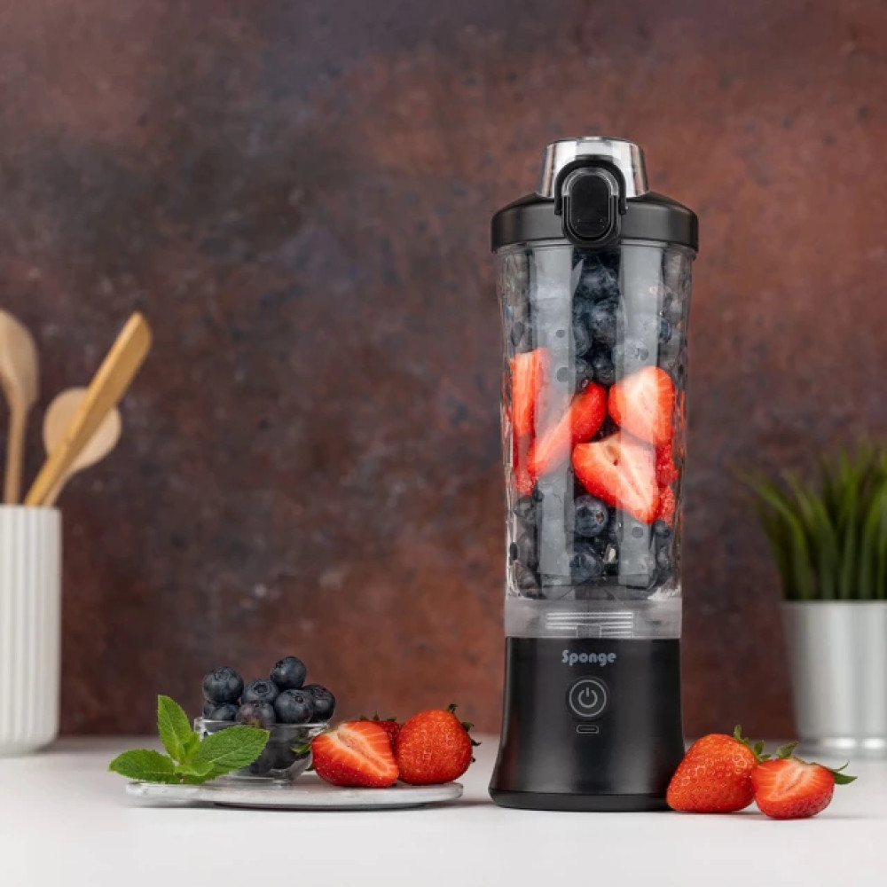 Przenośny blender wypełniony jagodami i truskawkami, obok owoce.