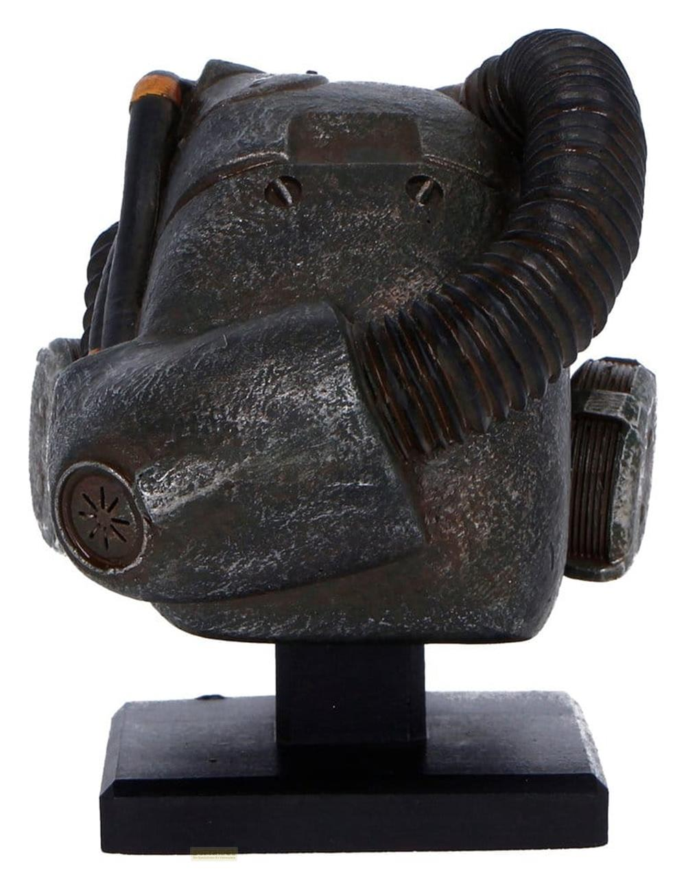 Eine dunkle, verwitterte Maske mit einem Schlauch und einem Lüftungsgitter, auf einem schwarzen Sockel.
