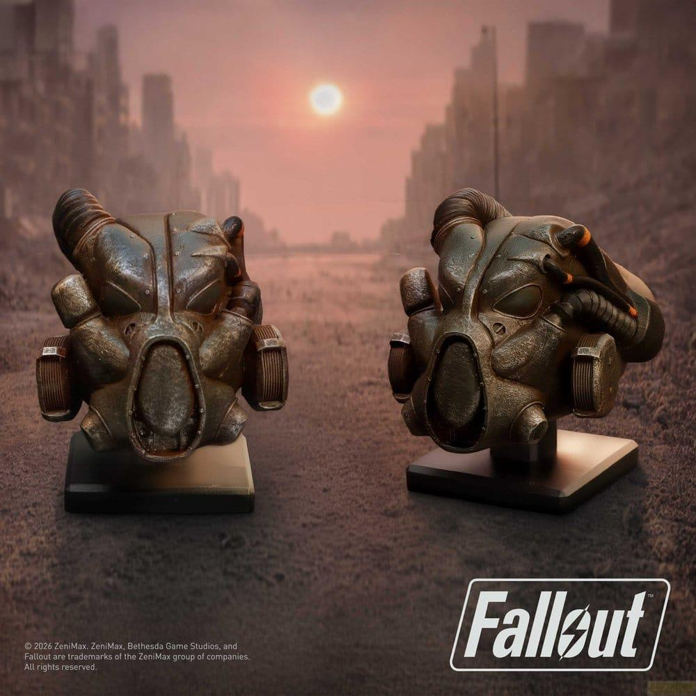 Zwei Fallout-Helme auf Podesten vor einer Stadtkulisse bei Sonnenuntergang.
