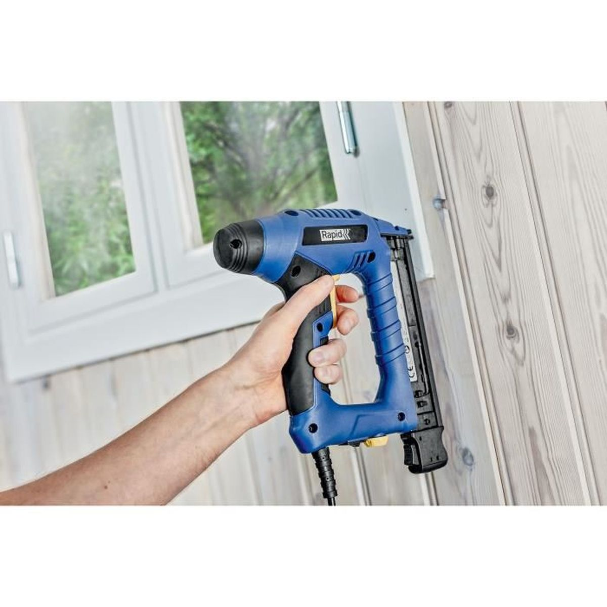 Una sparapunti blu è tenuta da una mano che fissa pannelli di legno.