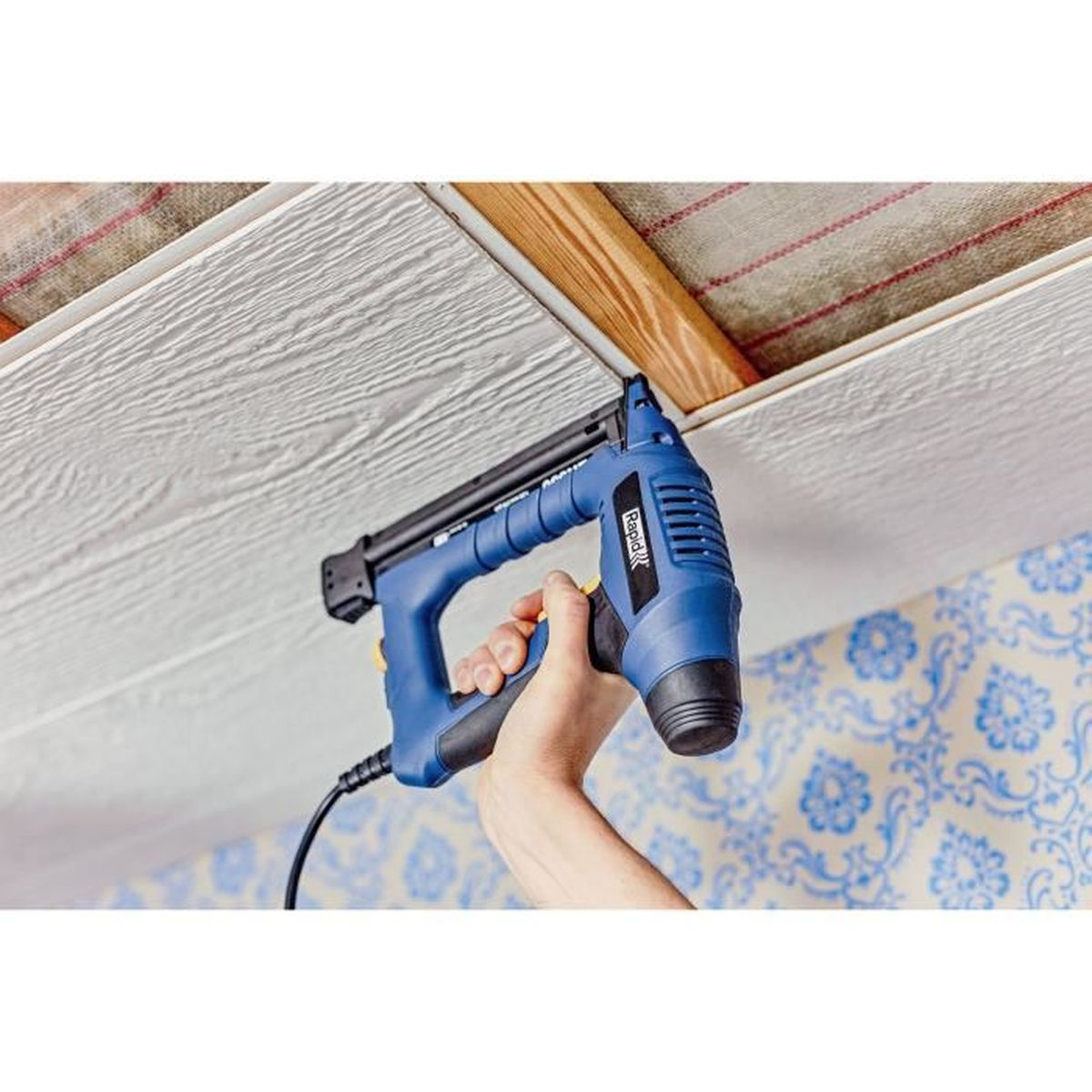 Una sparapunti Rapid blu fissa pannelli di legno bianchi a un soffitto.