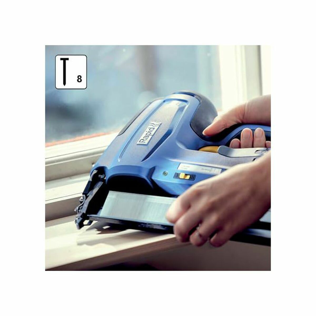 Pistola sparapunti blu Rapid tenuta dalle mani su una striscia di legno.