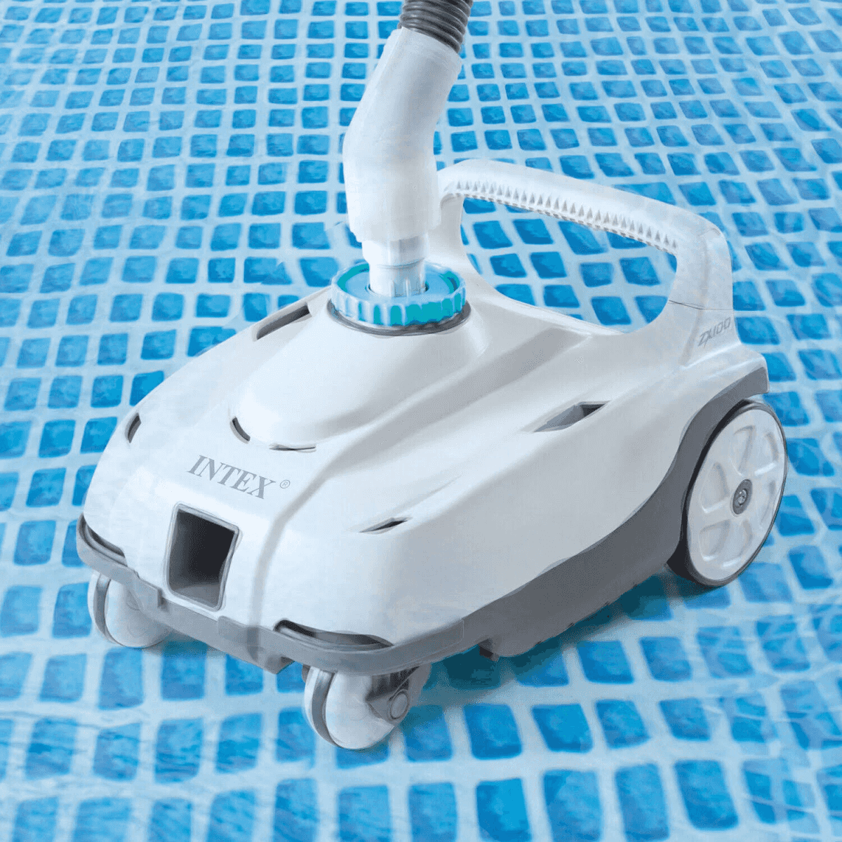 Biały robot basenowy z szarymi akcentami porusza się po niebieskiej, kafelkowej podłodze basenu.