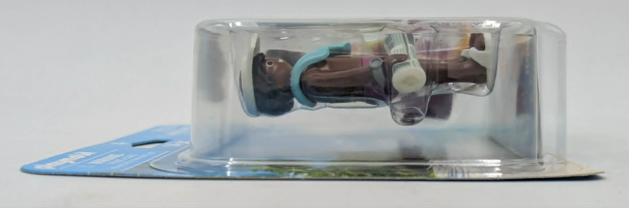 Una figura de Playmobil en embalaje de plástico, tumbada sobre cartón azul.
