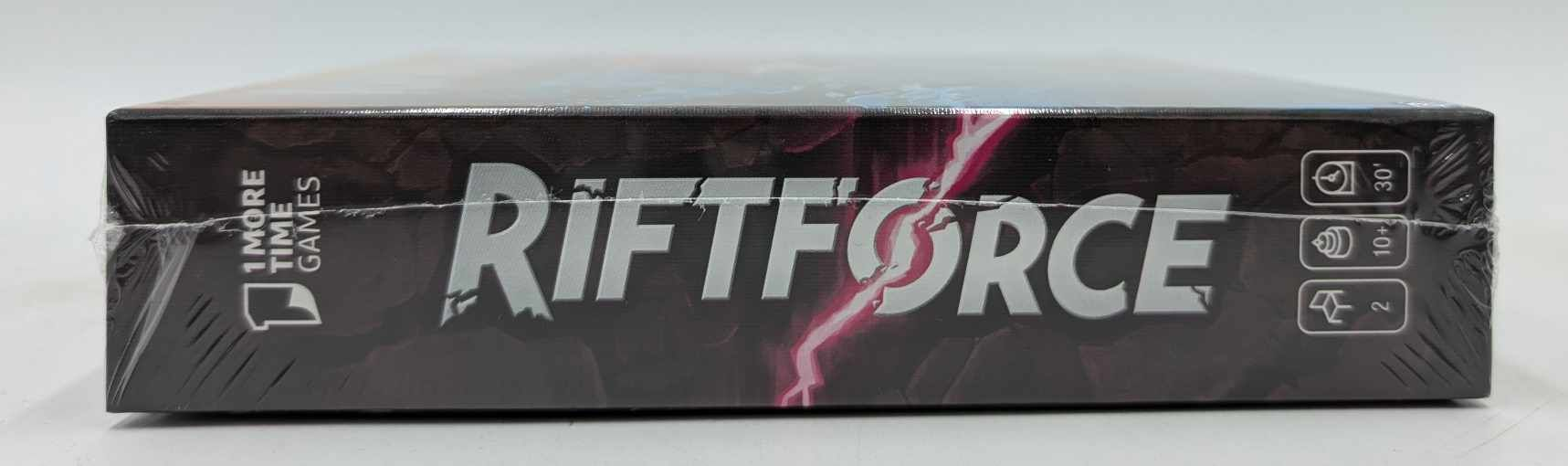 Die Brettspielhülle zeigt den Titel RIFTFORCE in Großbuchstaben, mit einer lila Blitzgrafik.