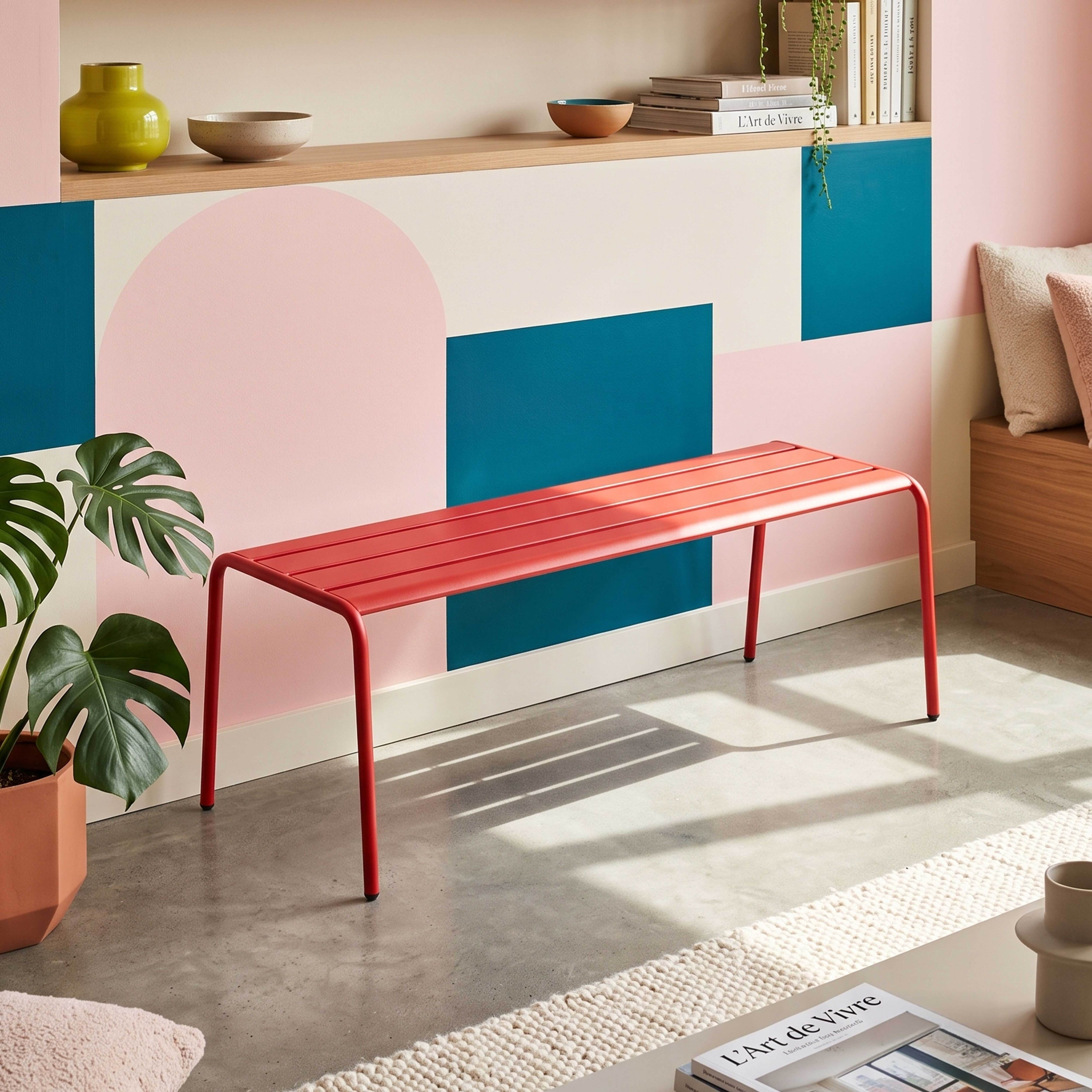 Ein roter Lamellenhocker steht vor einer Wand mit geometrischen Mustern.