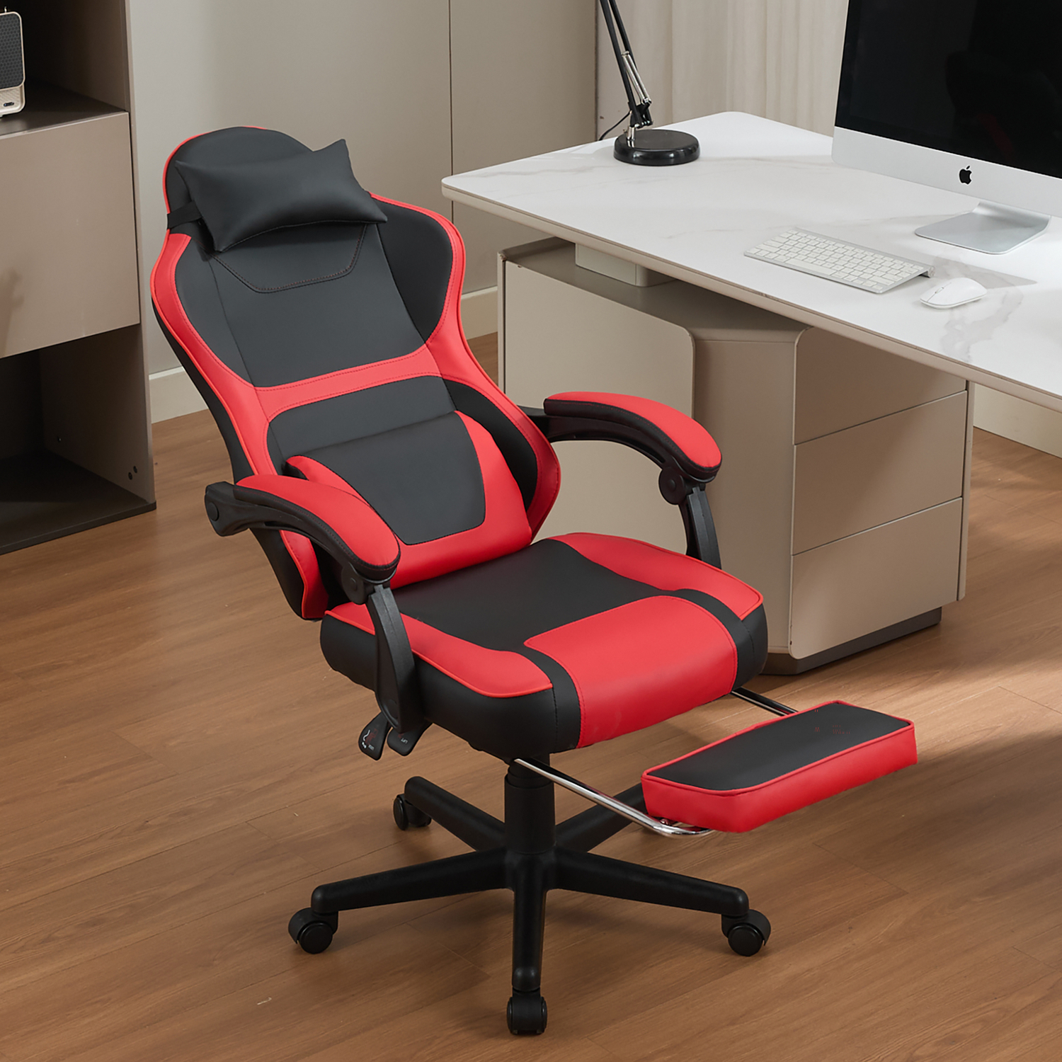 Ein rot-schwarzer Gaming-Stuhl mit Fußstütze steht neben einem Schreibtisch mit Computer.