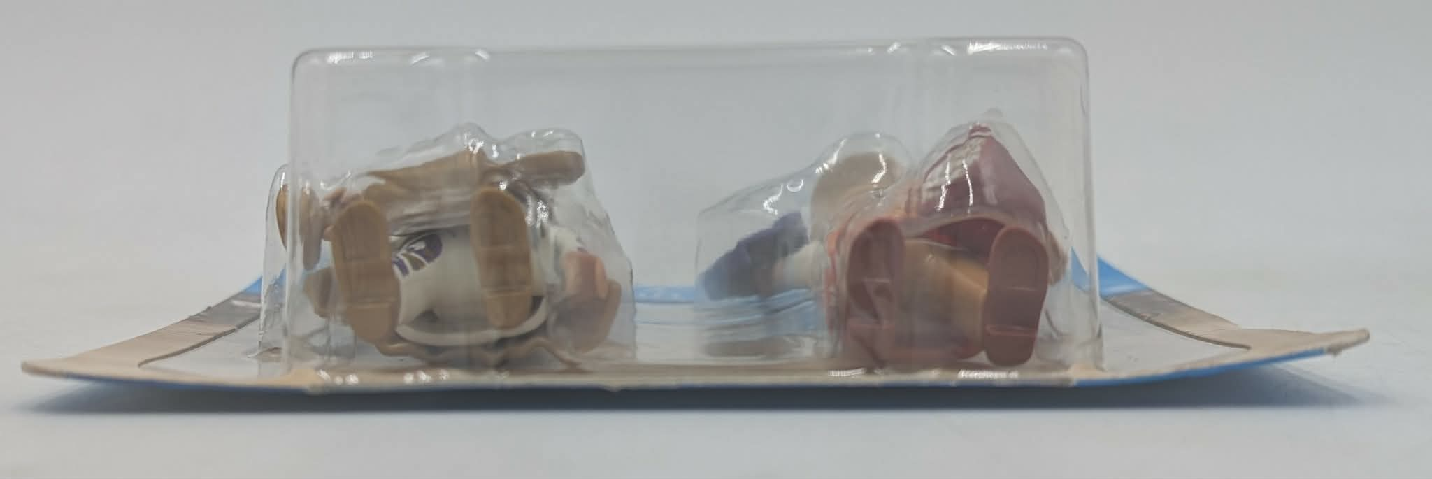 Due action figure in confezione di plastica, una con capelli castani, l'altra con vestiti rossi.