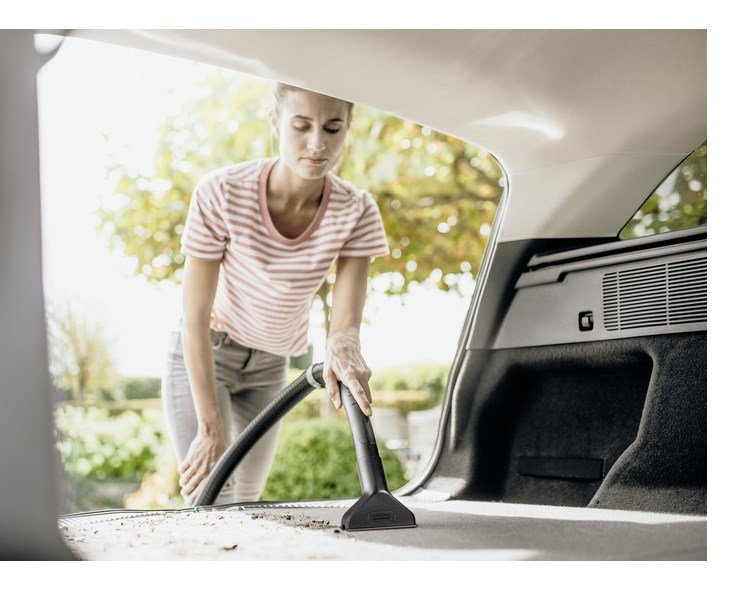 Una donna aspira il bagagliaio di un'auto all'aperto.
