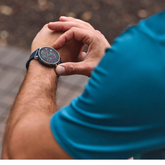 Un homme en tenue bleue regarde une montre connectée à son poignet.