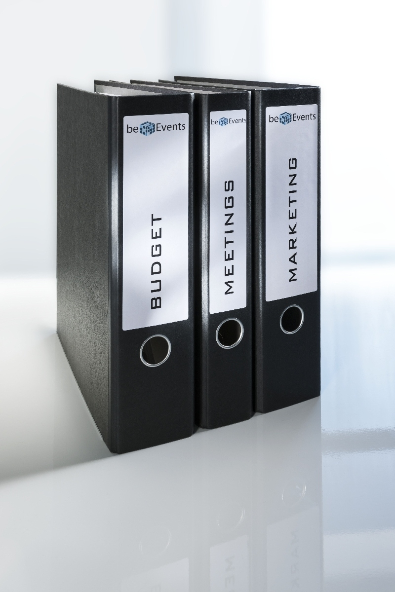 Drei schwarze Aktenordner nebeneinander: Budget, Meetings, Marketing.
