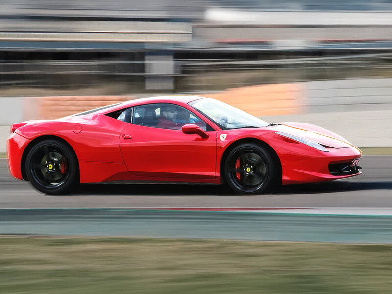 Un Ferrari rojo conduce rápido en una pista de carreras, con fondo borroso.