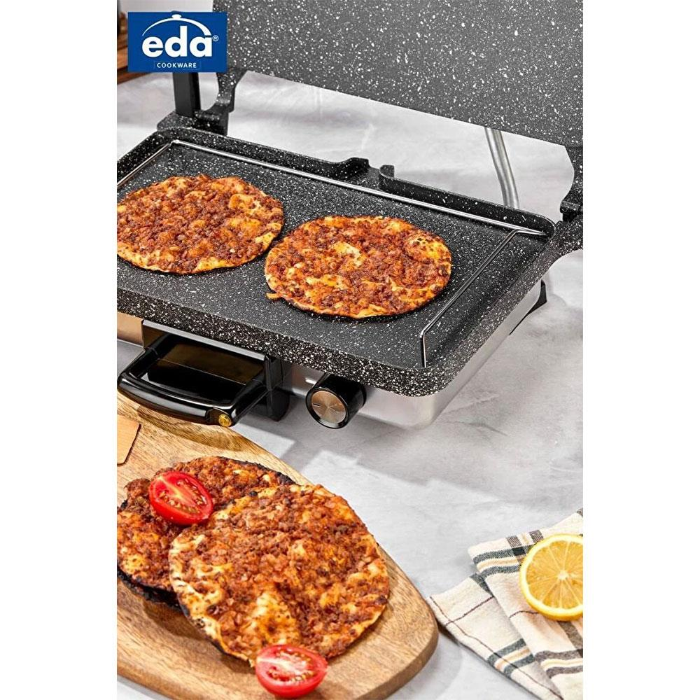 Üzerinde iki pizza olan bir kontaktlı ızgara ve yanında tahta üzerinde domatesli iki pizza.