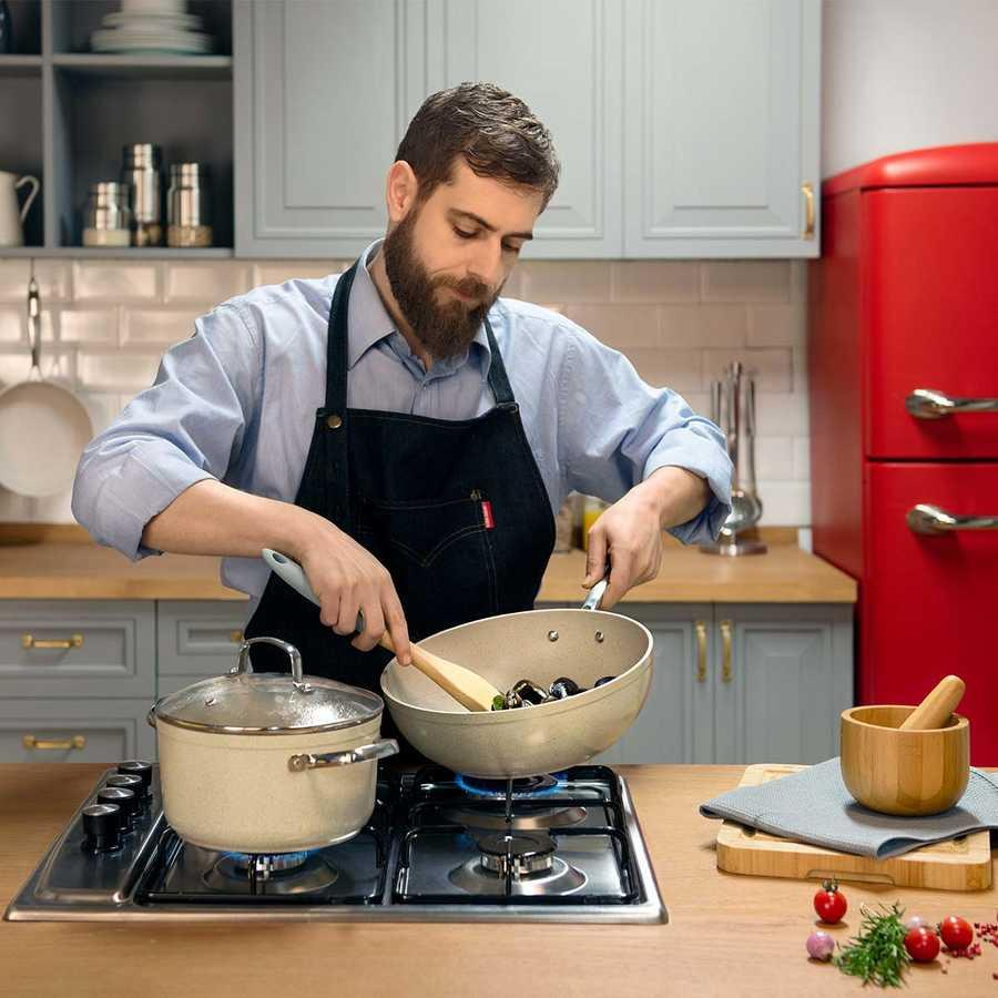 Sakallı adam gazlı ocakta tavada midye pişiriyor.