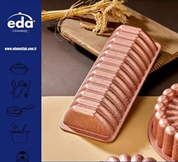 Kanallı girintilere sahip pembe kek kalıbı ahşap bir tepsinin üzerinde duruyor.