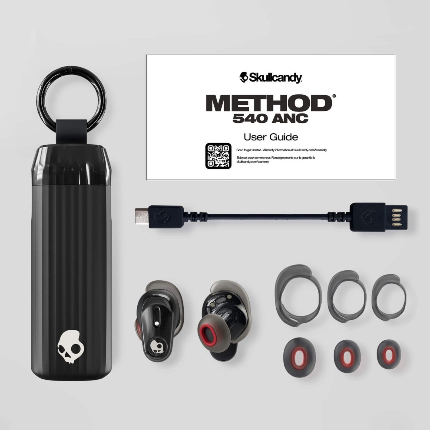 Skullcandy kulaklıklar, şarj kutusu, USB kablosu ve kulak uçları beyaz arka planda.